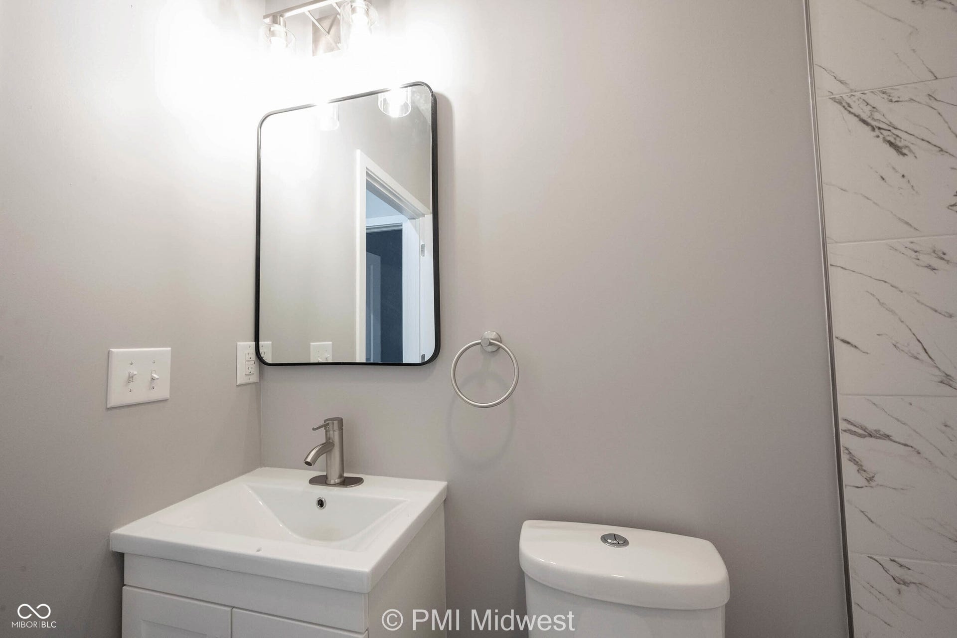 Bathroom featuring a white vanity with integrated sink, brushed nickel faucet, and a contemporary framed mirror