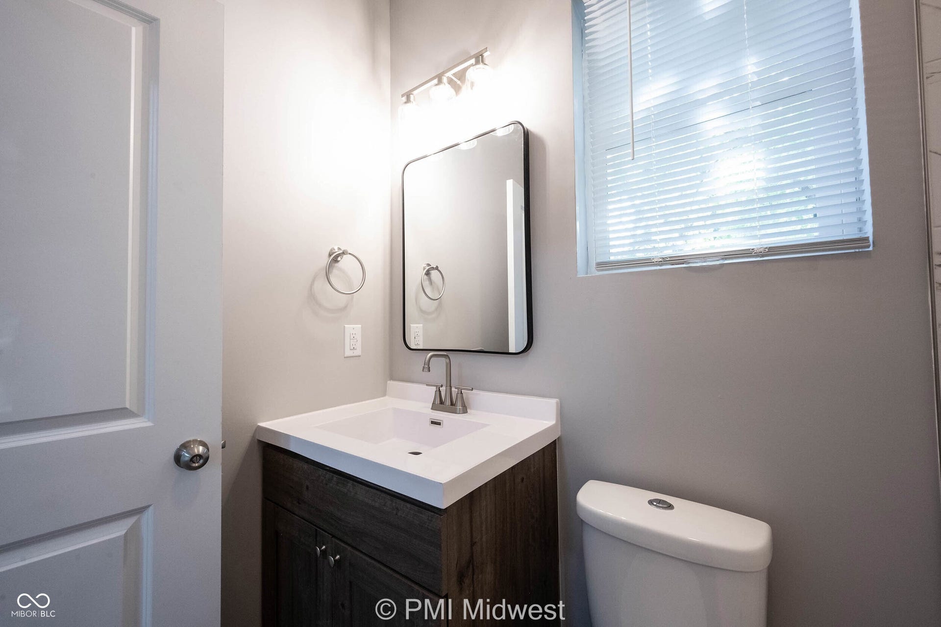 Bathroom featuring a wood-finish vanity with an integrated sink and a rectangular mirror