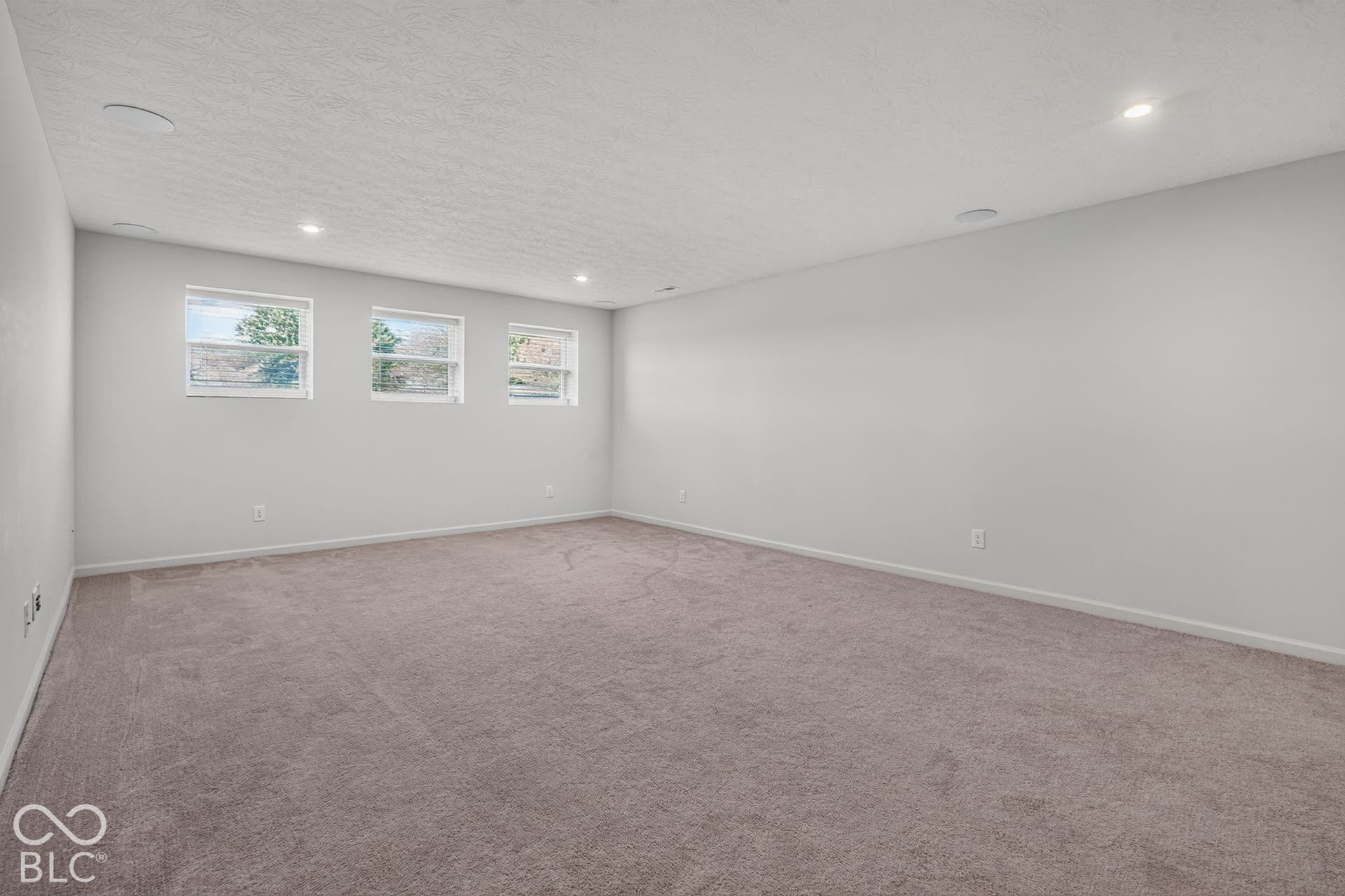 Neutral interior space featuring wall-to-wall carpeting, recessed ceiling lighting, and three rectangular windows