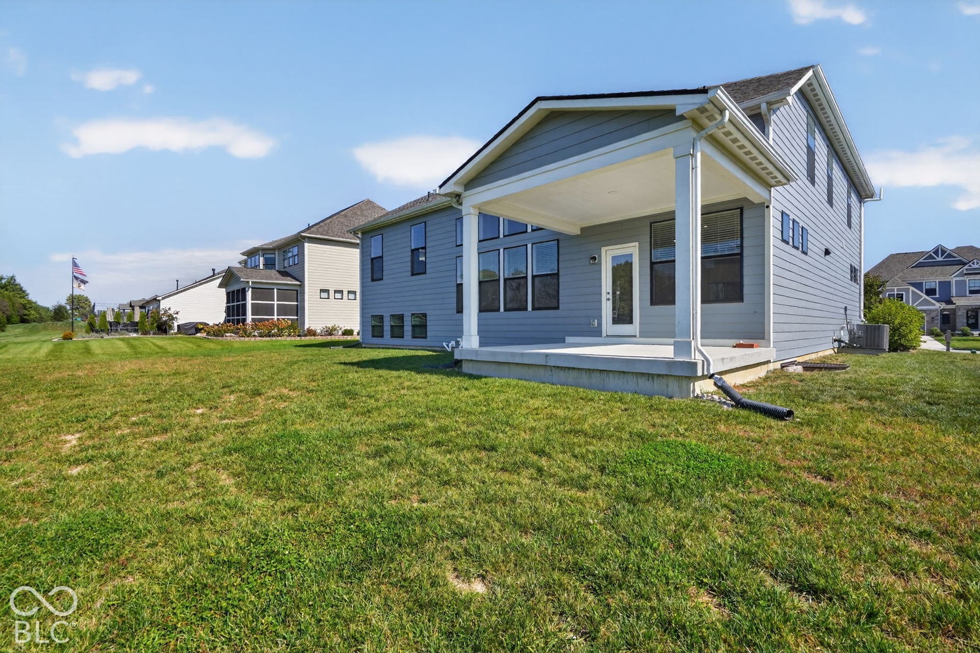 Blue lap siding exterior featuring a covered rear patio, a concrete foundation, and multi-pane windows