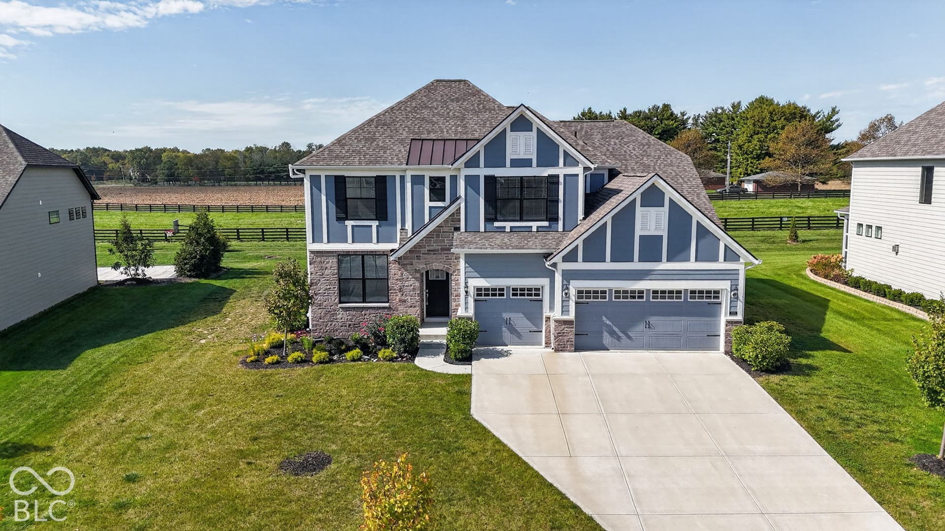 Two-story exterior featuring stone veneer and vertical siding, multi-gabled roofline, front-facing three-car garage, and concrete driveway