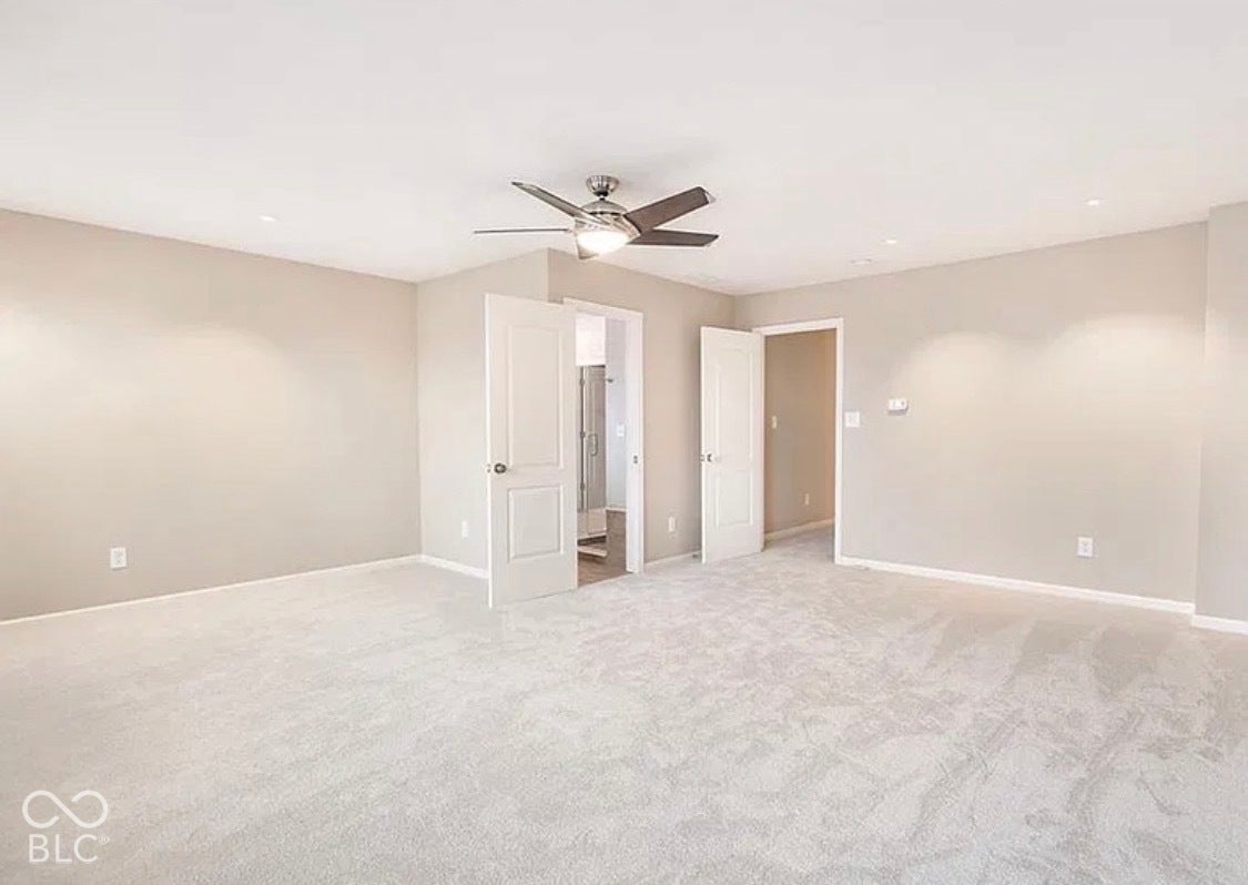 Neutral wall-to-wall carpeting, recessed ceiling lighting, and a multi-blade ceiling fan with integrated light fixture