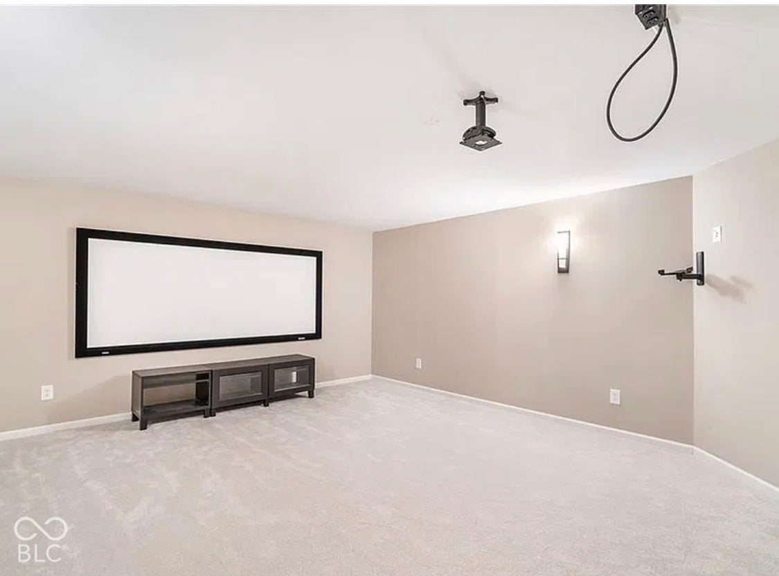 Interior room featuring wall-to-wall carpeting, a fixed wall-mounted projection screen, and integrated wall-mounted lighting