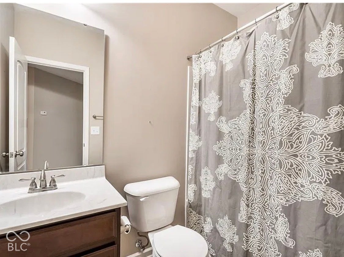 Bathroom featuring a dark wood-finish vanity, light-toned countertop, undermount sink with a polished chrome faucet, and a wall-mounted mirror