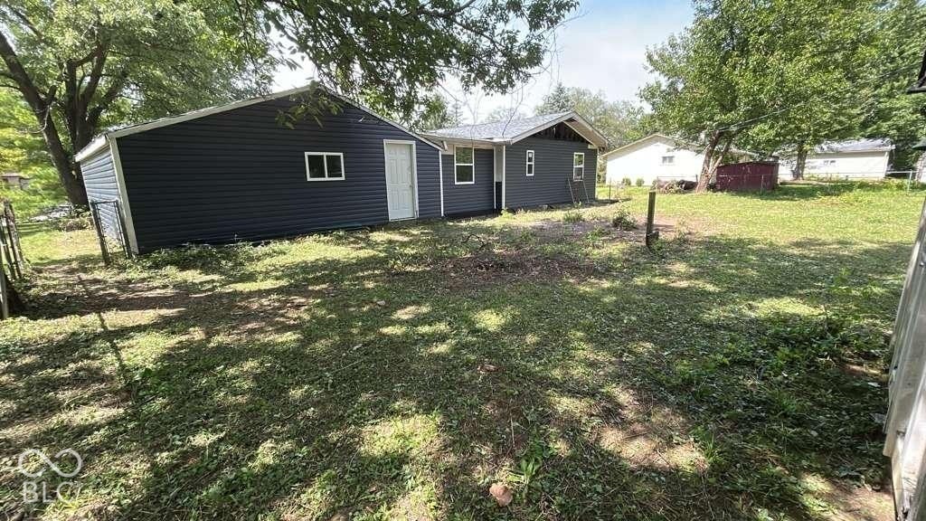 Exterior featuring dark blue horizontal siding, white trim, and a grass-covered backyard
