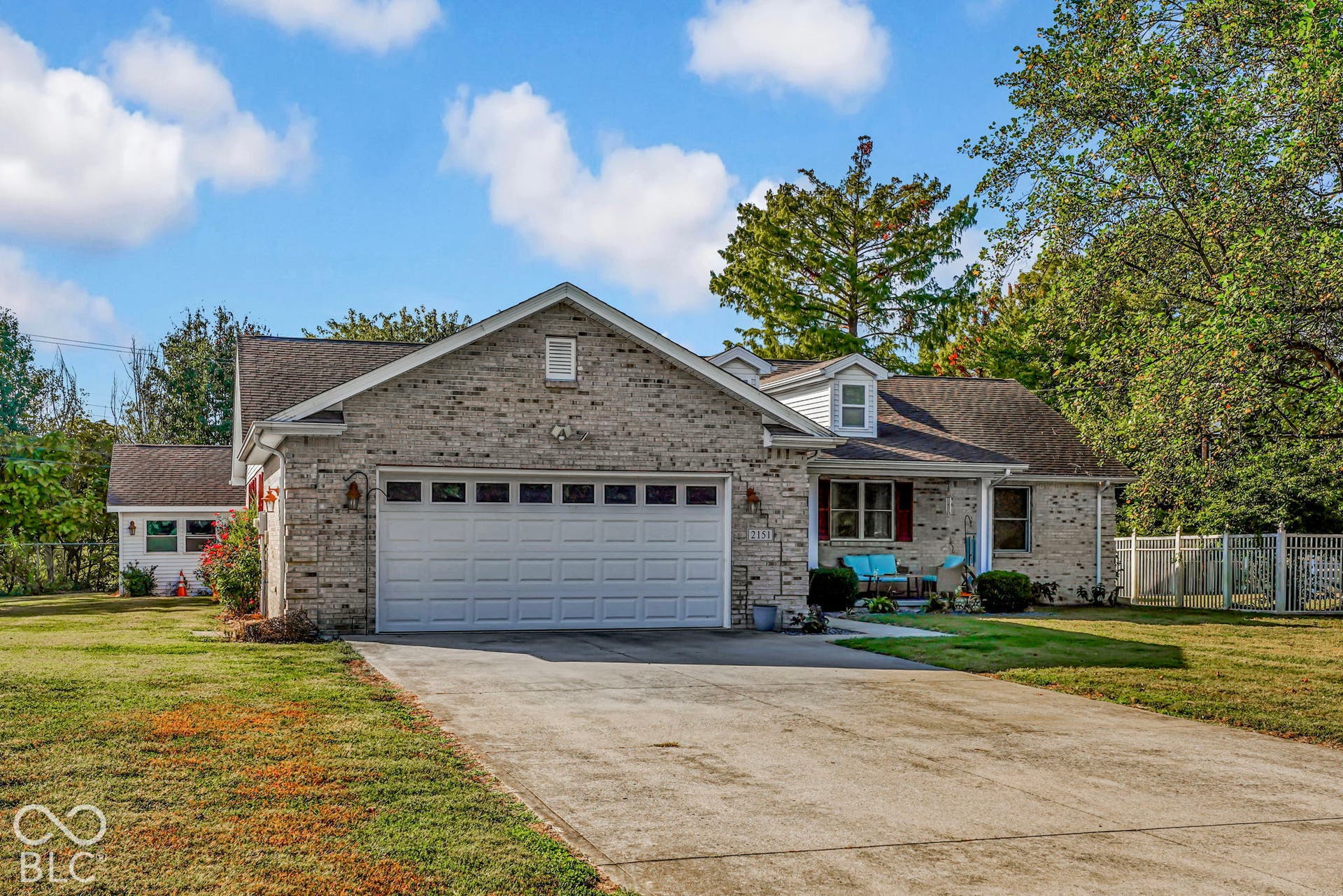 Single-story brick exterior featuring a front-facing attached garage, concrete driveway, and dormer window detail