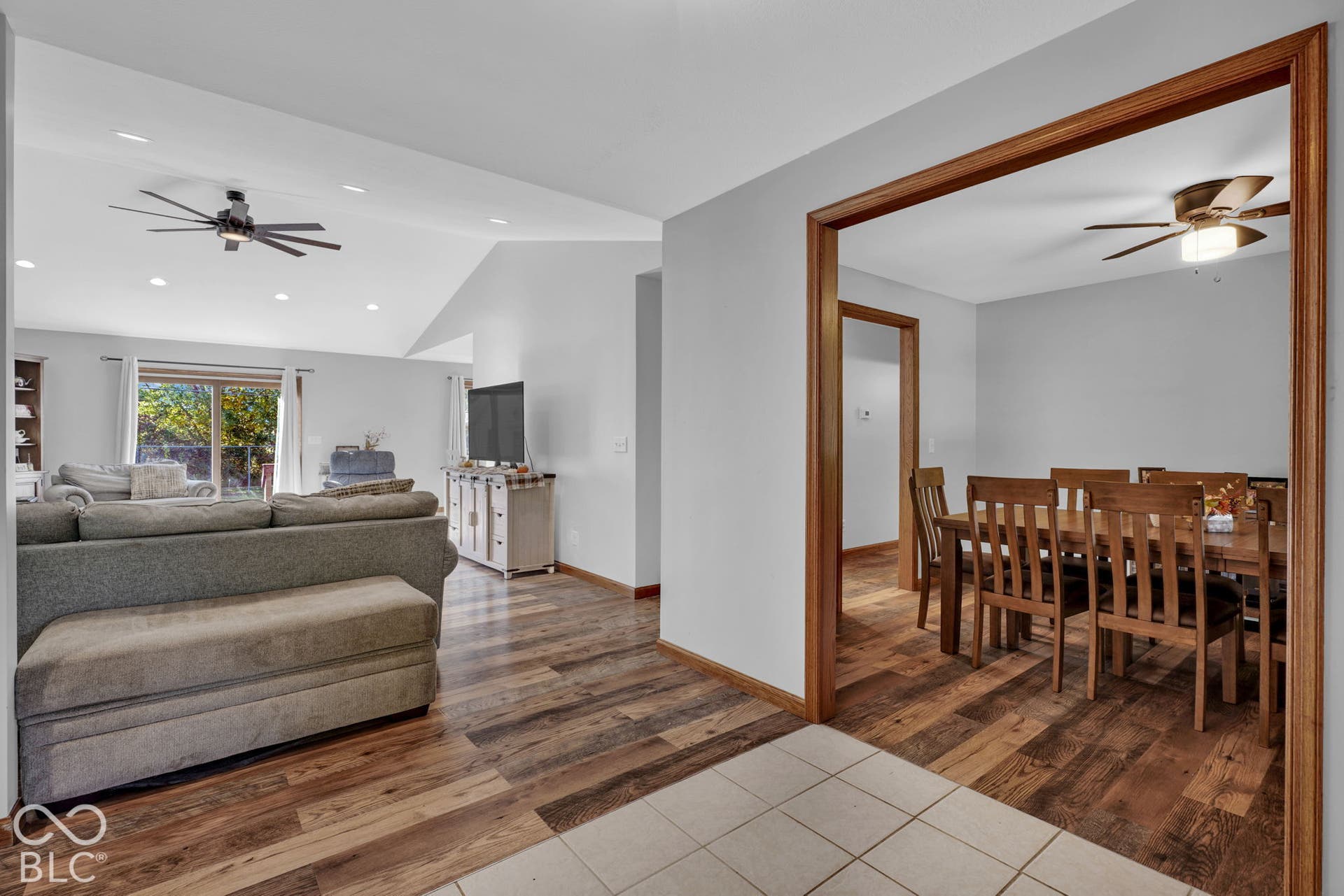 Vaulted ceilings with recessed lighting, wood-finish flooring, and natural wood door trim