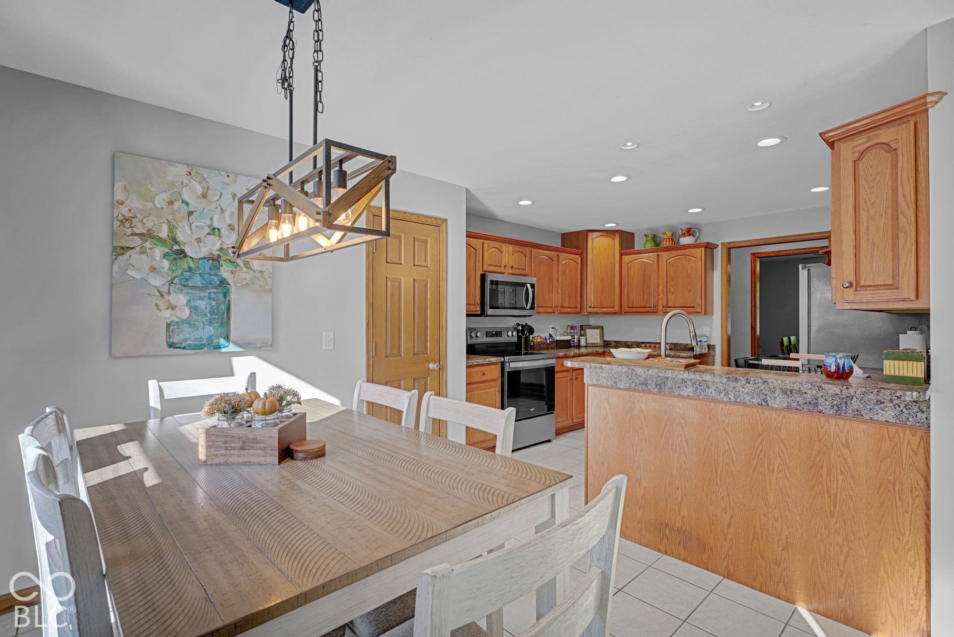 Kitchen featuring oak cabinetry, laminate countertops, stainless steel appliances, recessed ceiling lighting, and a linear cage-style pendant fixture