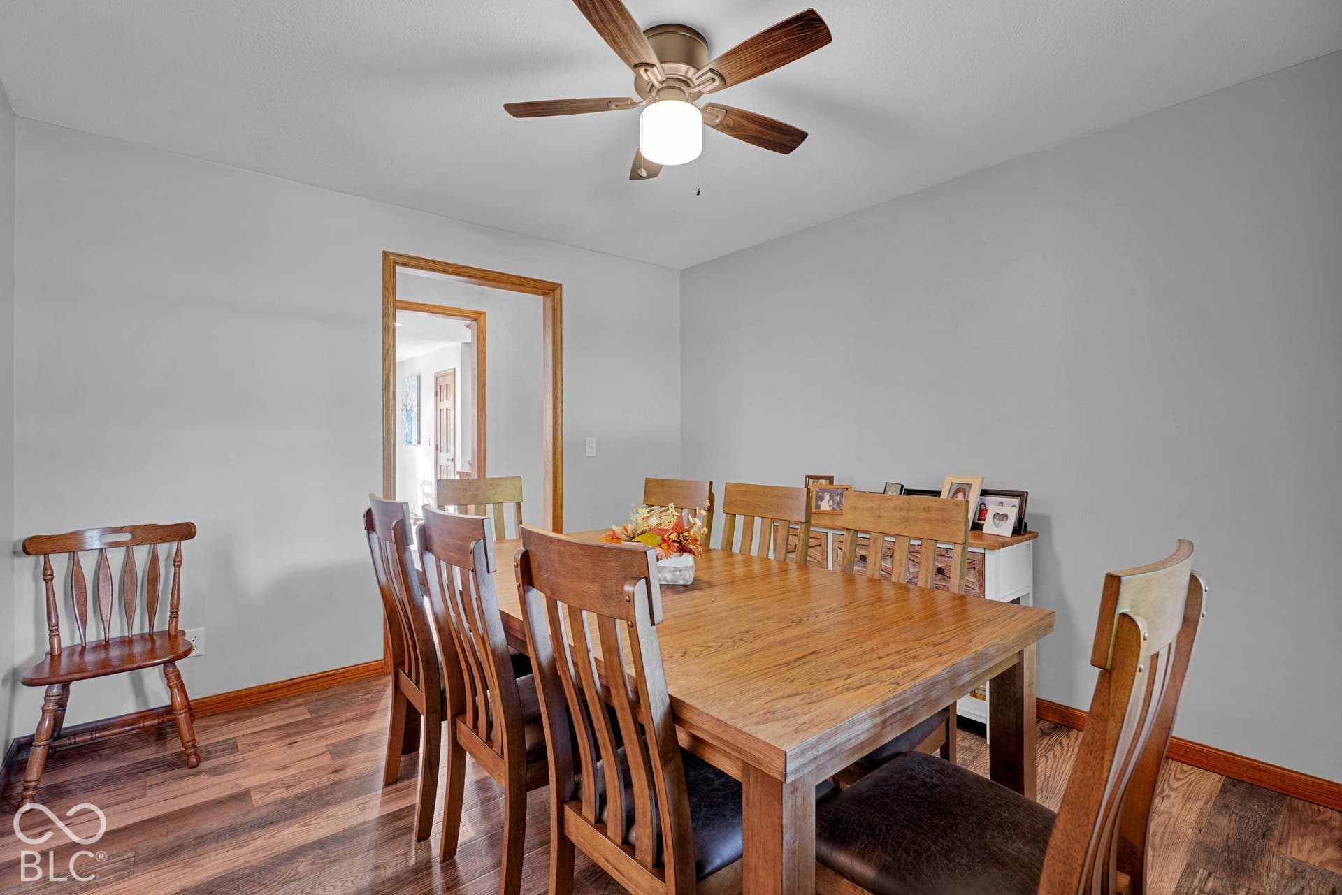 Wood-finish flooring, neutral wall color, and a ceiling-mounted light fixture with a fan