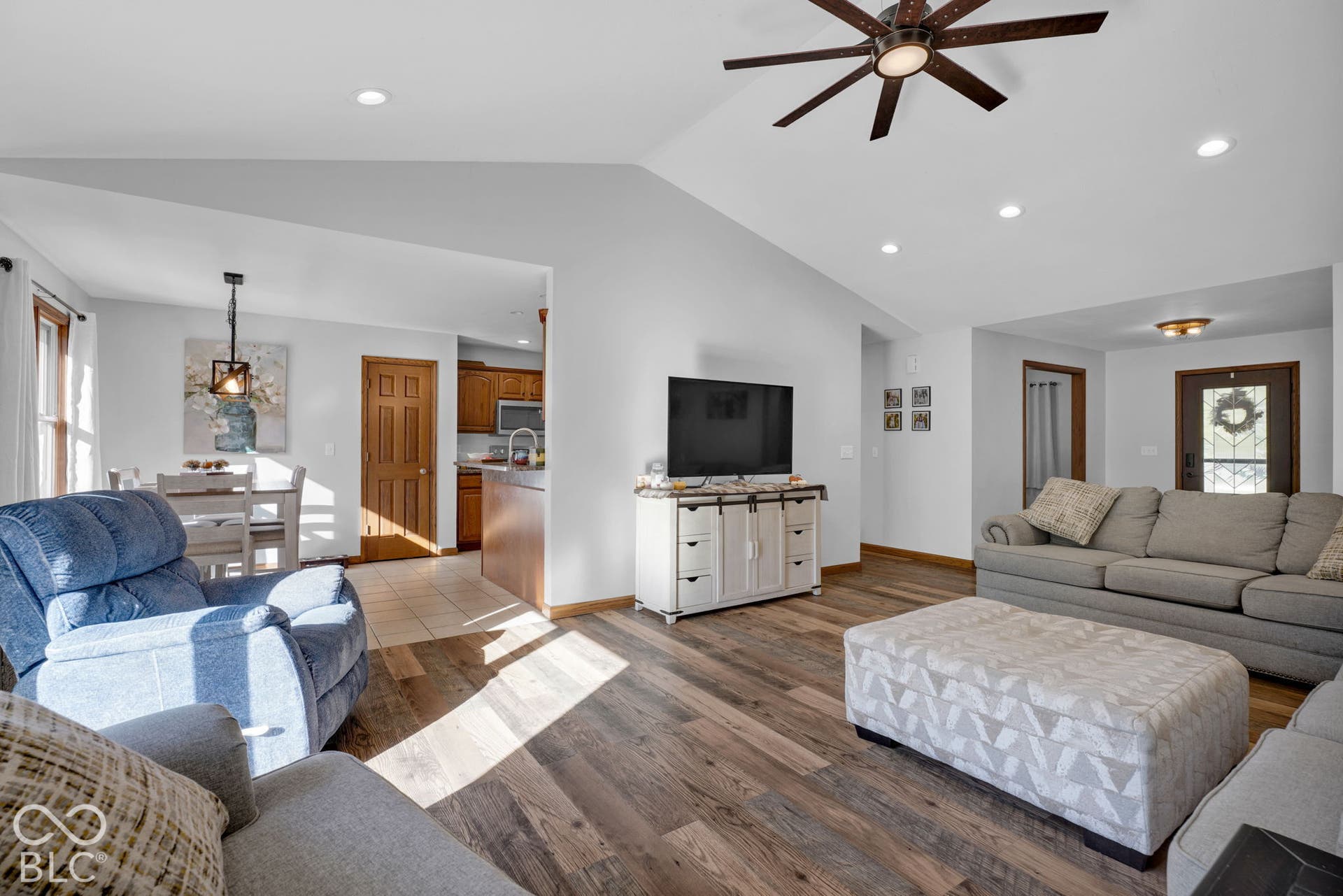 Vaulted ceilings, wood-finish flooring, recessed lighting, and a multi-blade ceiling fan