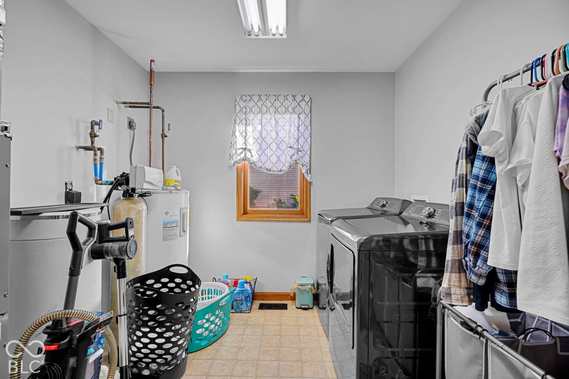 Dedicated laundry area featuring a central window, water treatment system, and tile flooring