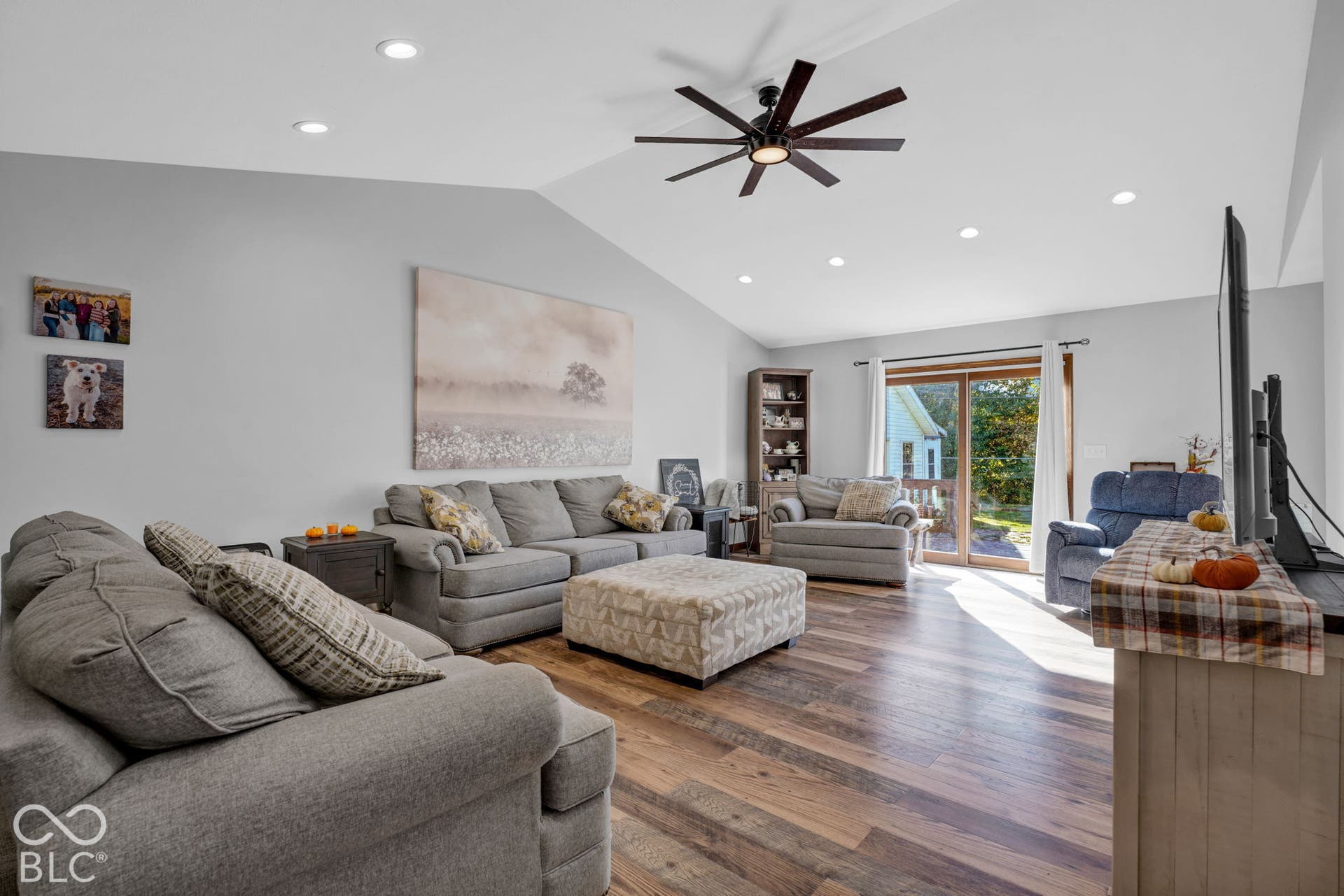 Living area featuring vaulted ceilings, wood-finish flooring, recessed lighting, a modern ceiling fan, and sliding glass doors
