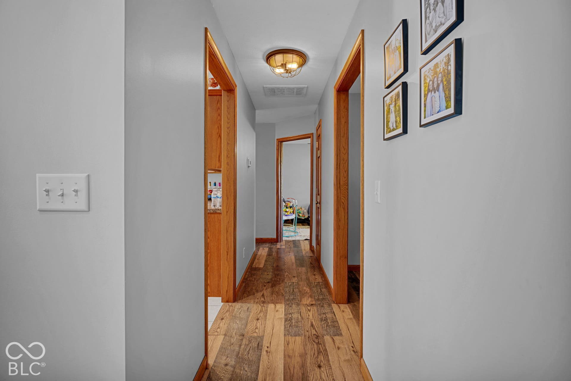 Hallway featuring wood-finish flooring, natural wood door casing, and a flush-mount drum ceiling light fixture