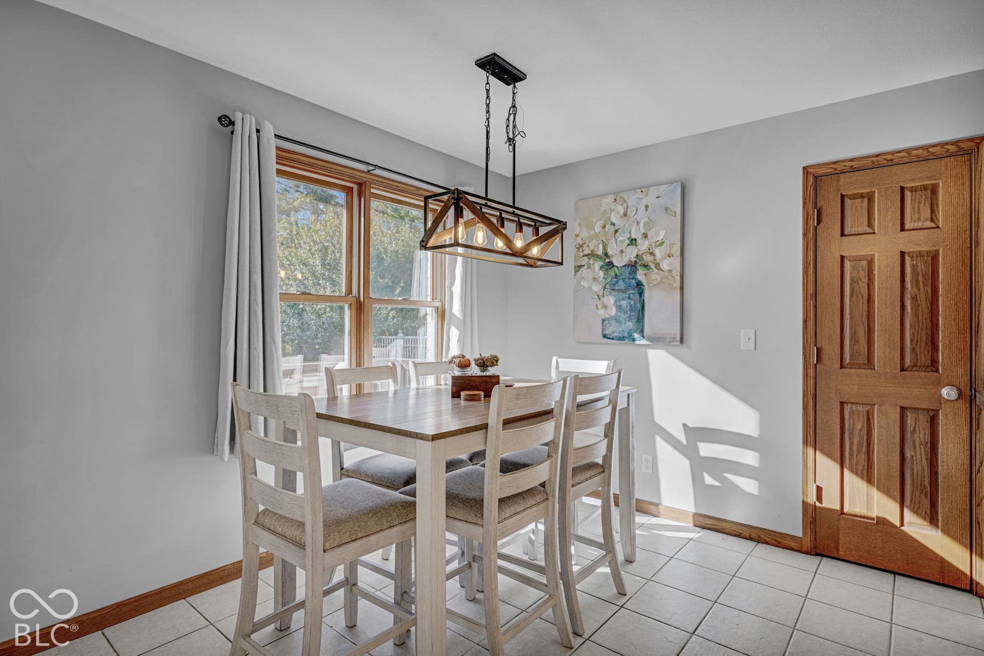 Ceramic tile flooring, six-panel wood door with matching trim, and a linear metal pendant light fixture featuring an exposed frame