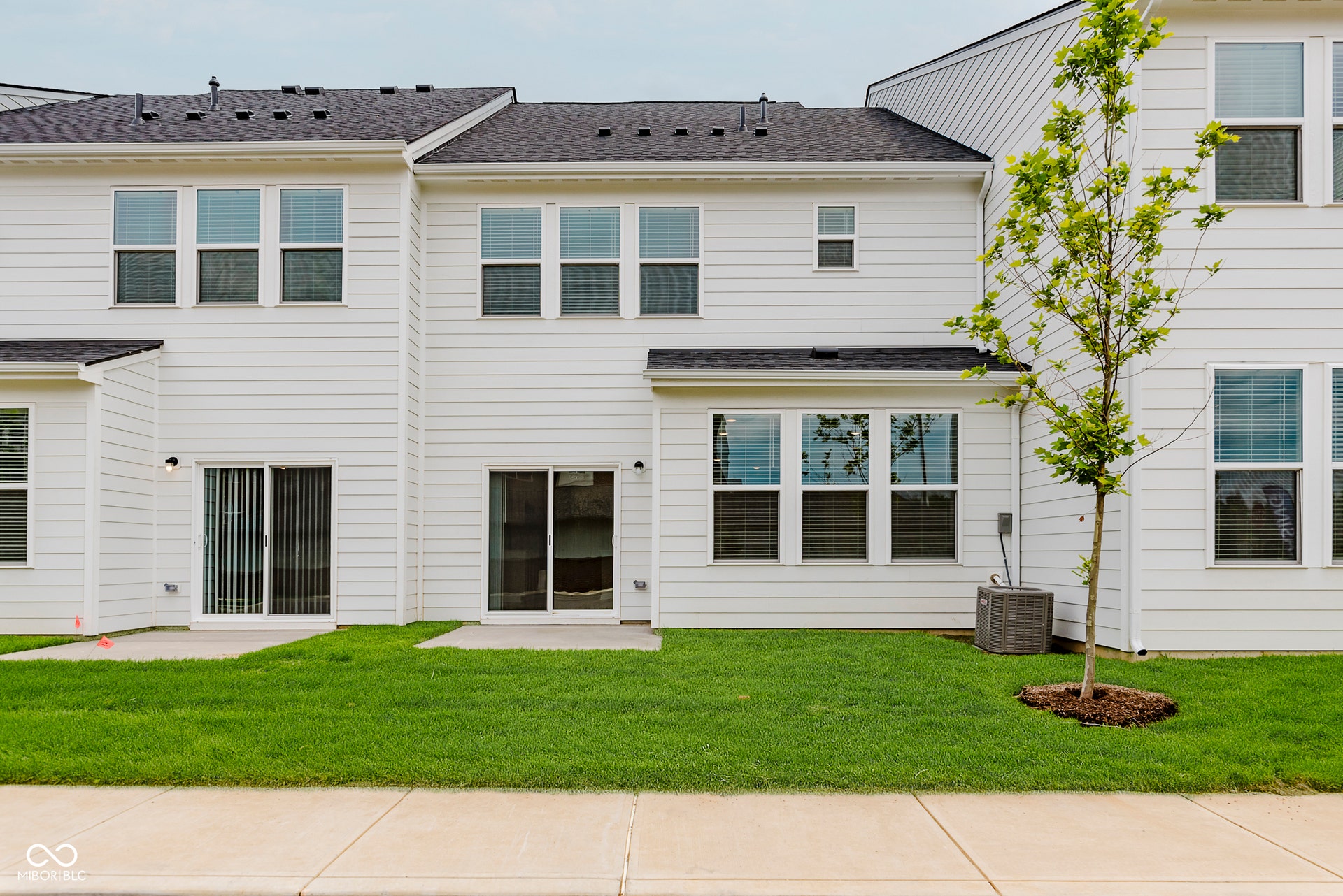 back of property featuring a yard, a patio area, and roof with shingles