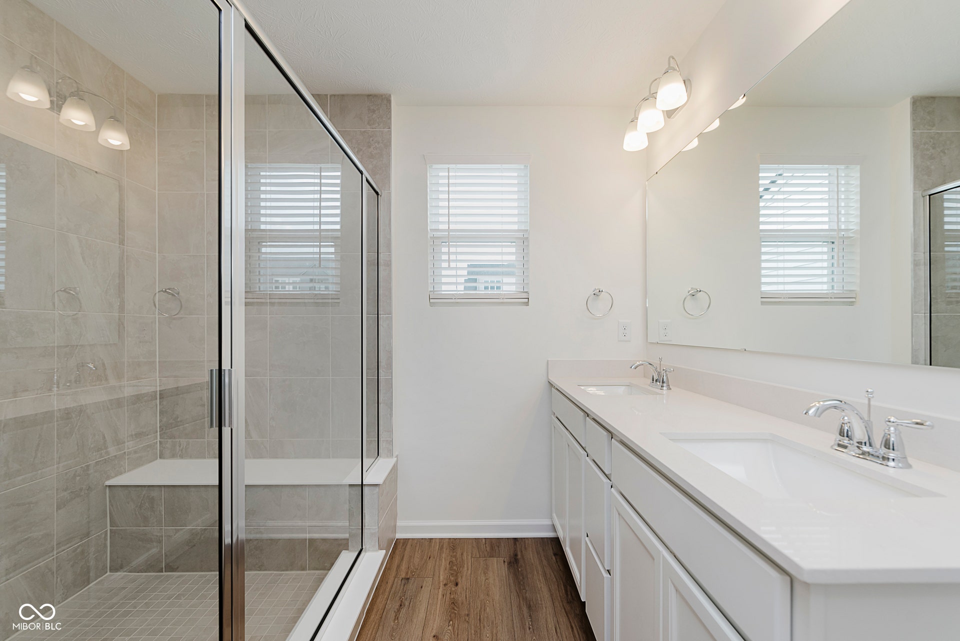 bathroom featuring dark wood-type flooring, double vanity, and a stall shower