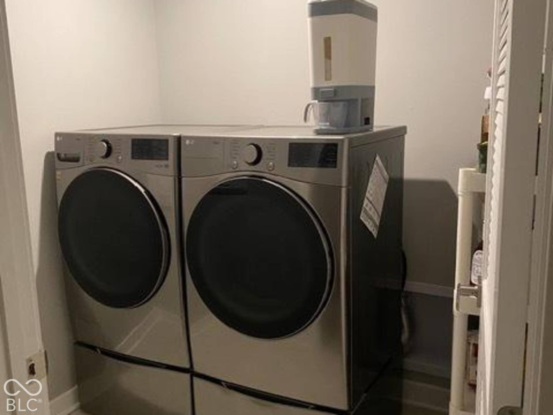 Dedicated laundry closet featuring stainless steel front-load appliances and storage pedestals