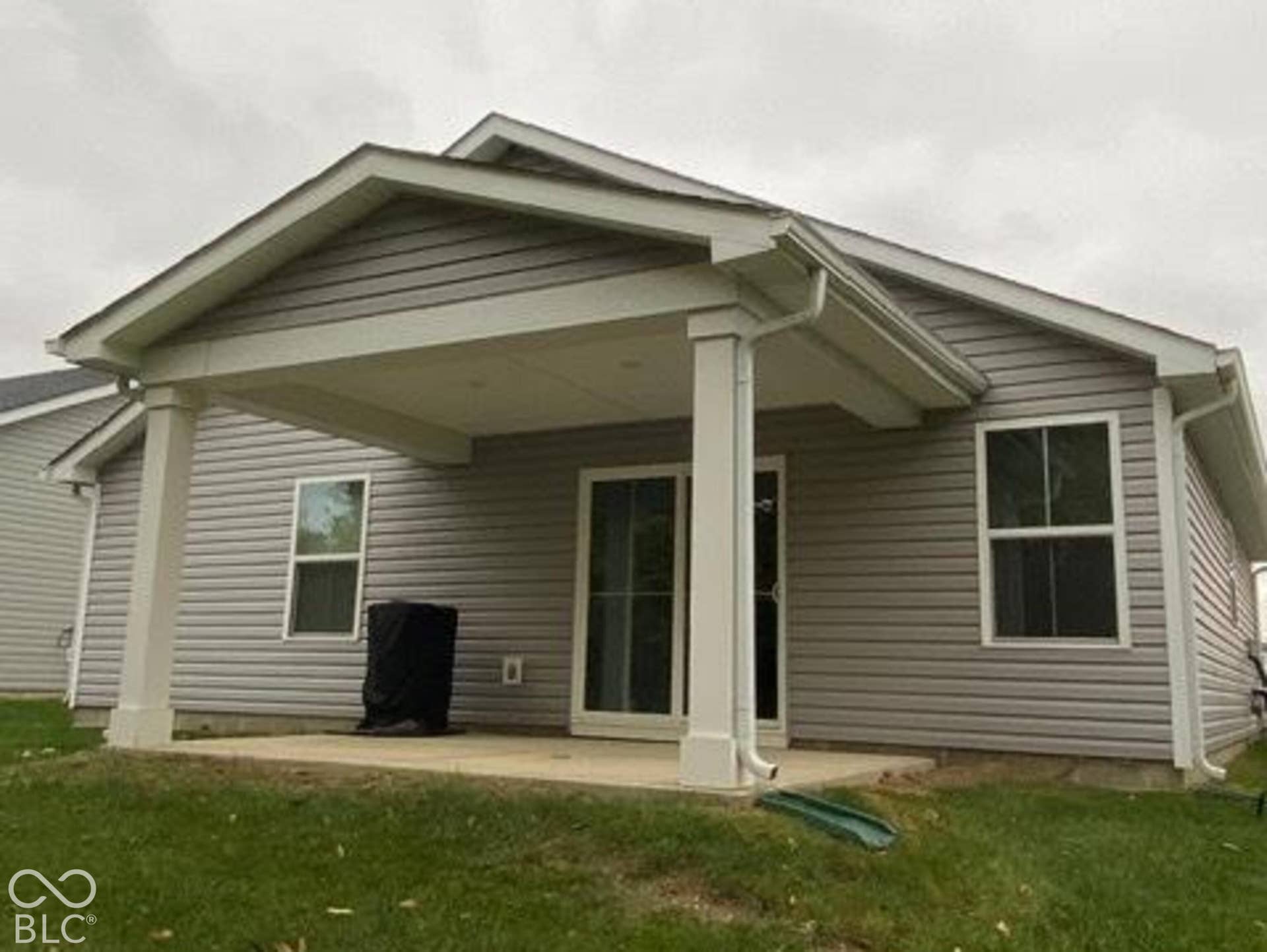 Rear exterior featuring horizontal lap siding, a covered concrete patio, and structural support columns