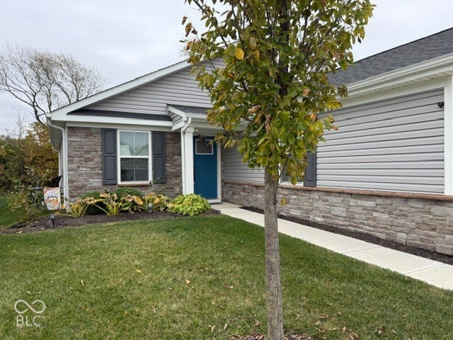 Charming single-story home featuring a brick and vinyl exterior, welcoming blue entry door, and mature landscaping with established trees