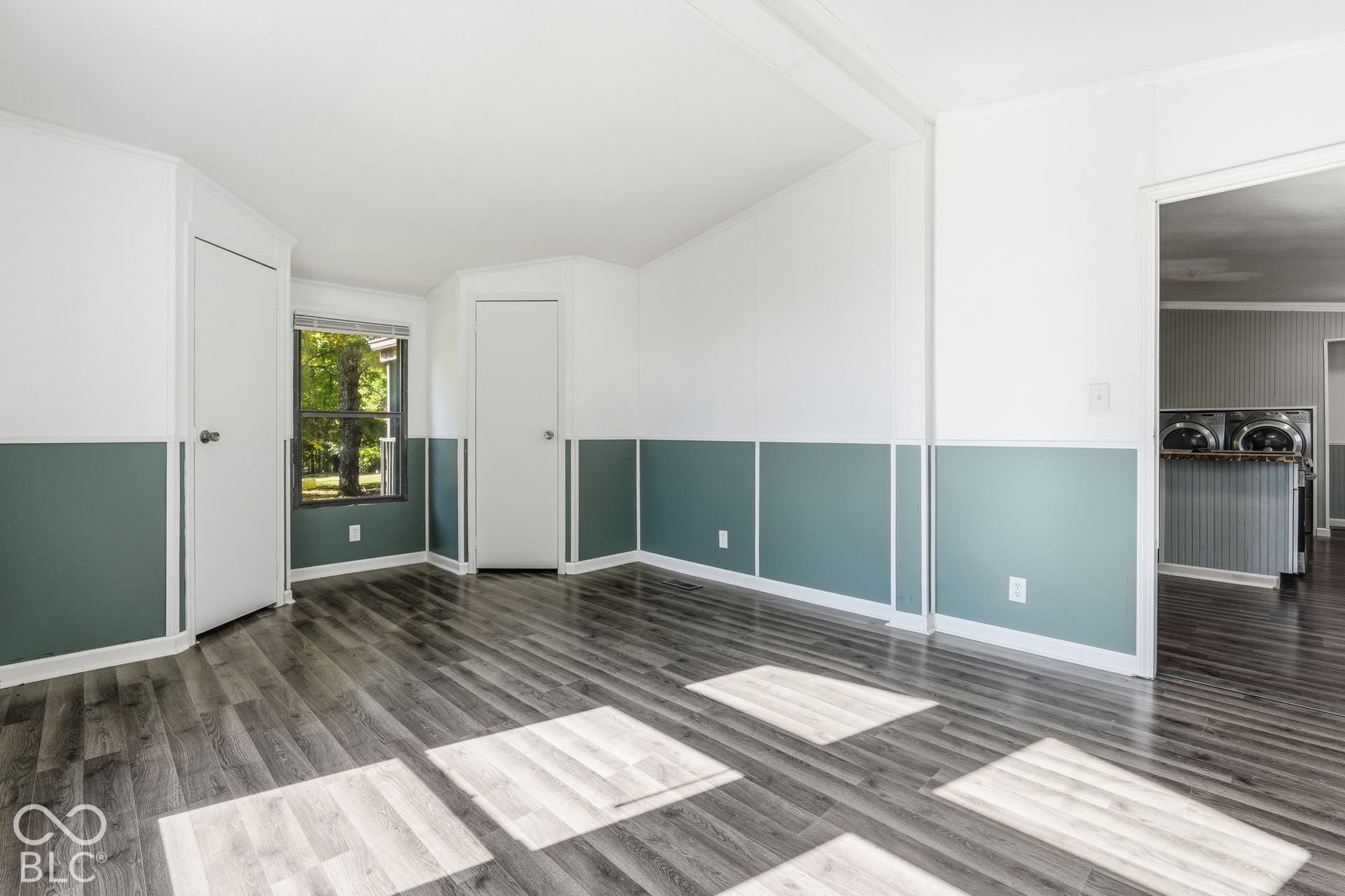 Interior space featuring wood-finish flooring, two-tone wall treatments, wainscoting, and a single-pane window