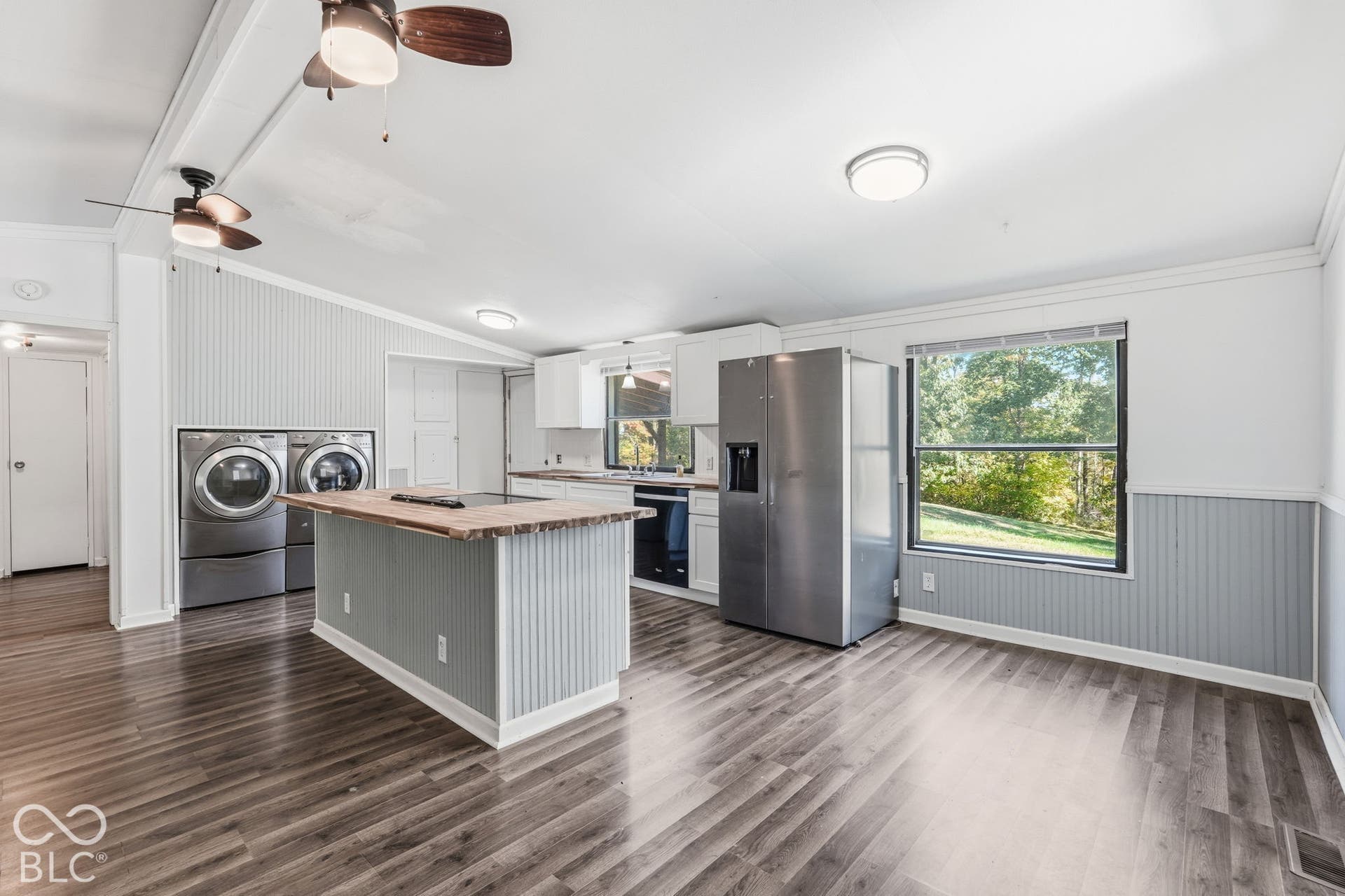 Kitchen featuring white cabinetry, wood-finish island countertop, wood-finish flooring, beadboard wall paneling, and stainless steel appliances