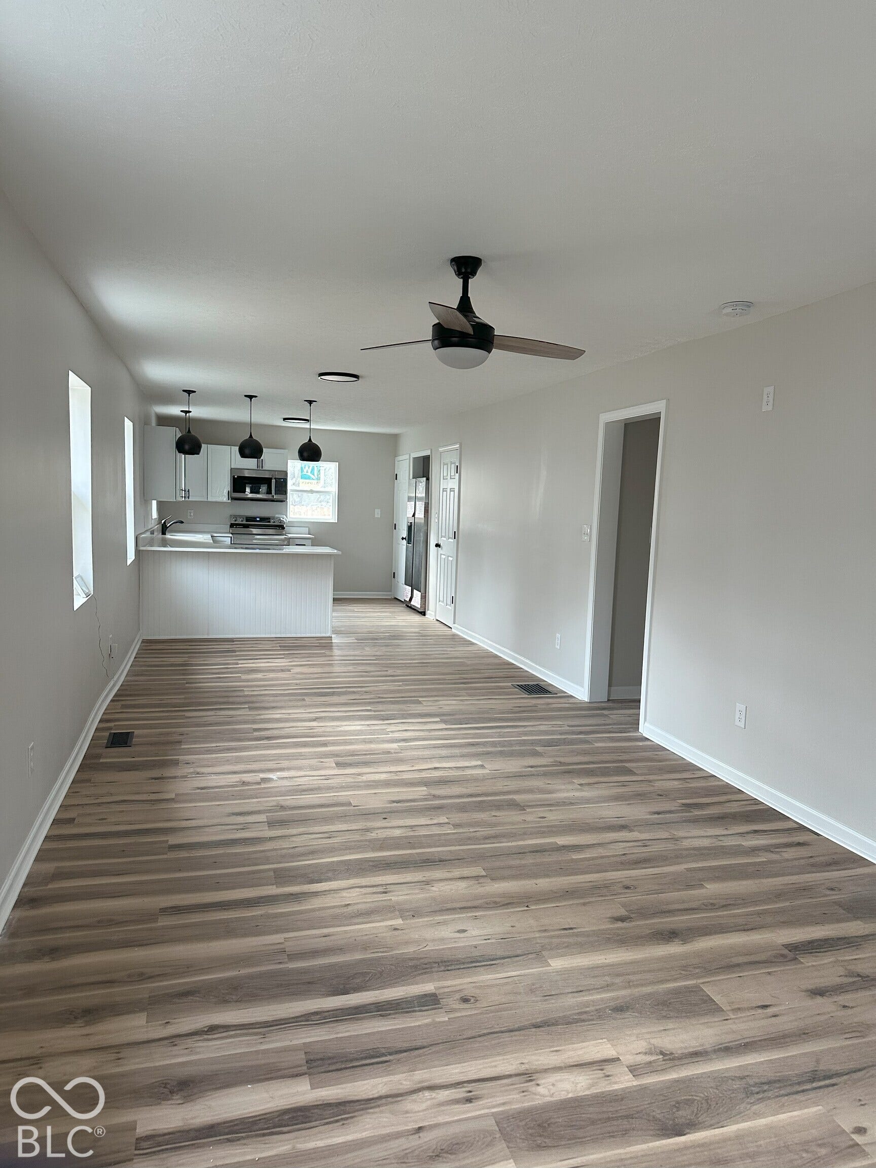 Open concept interior featuring wood-finish flooring, recessed lighting, a ceiling fan, and a kitchen peninsula with pendant lighting
