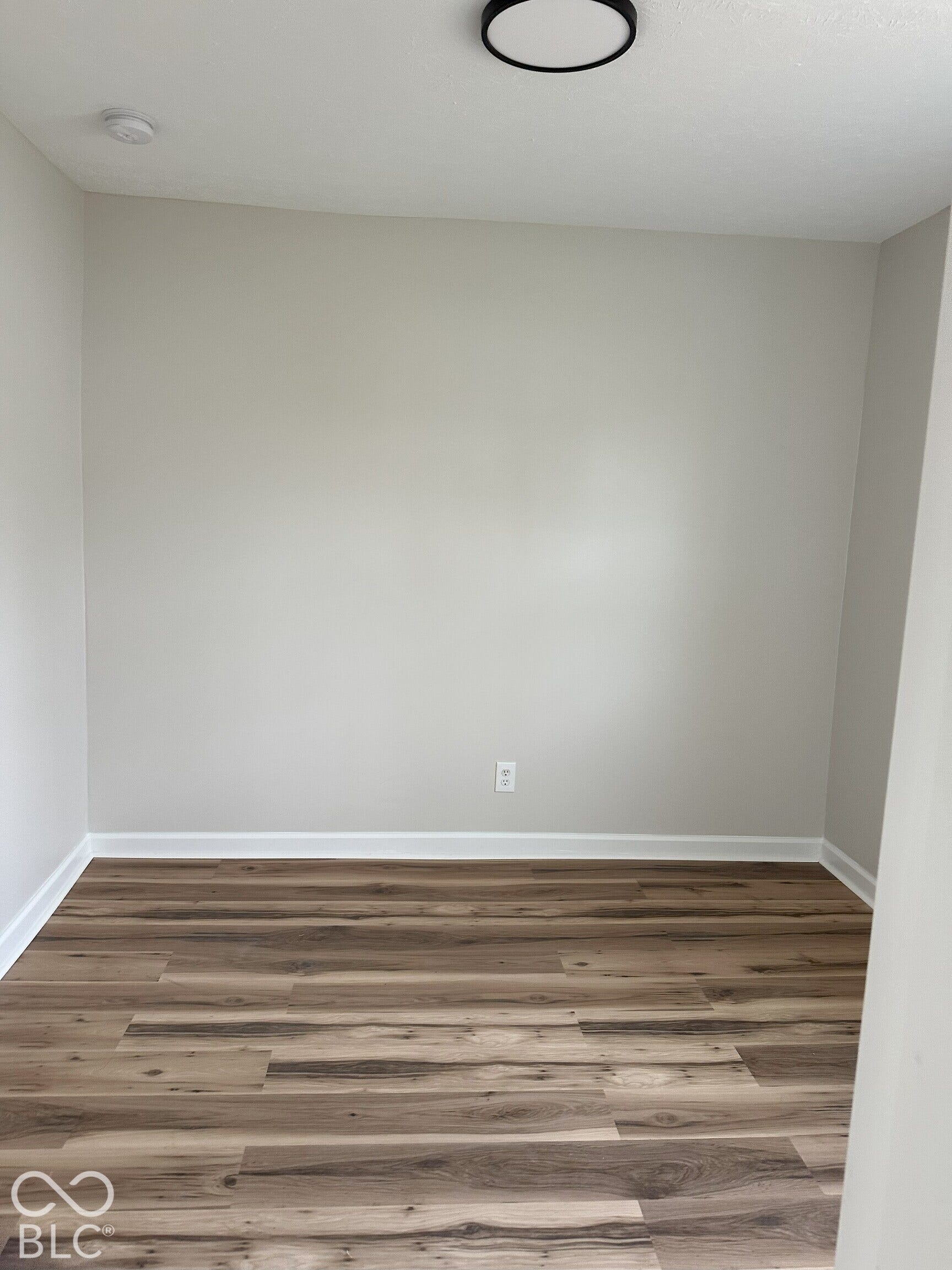 Neutral wall paint, wood-finish flooring, and a circular low-profile flush-mount ceiling fixture