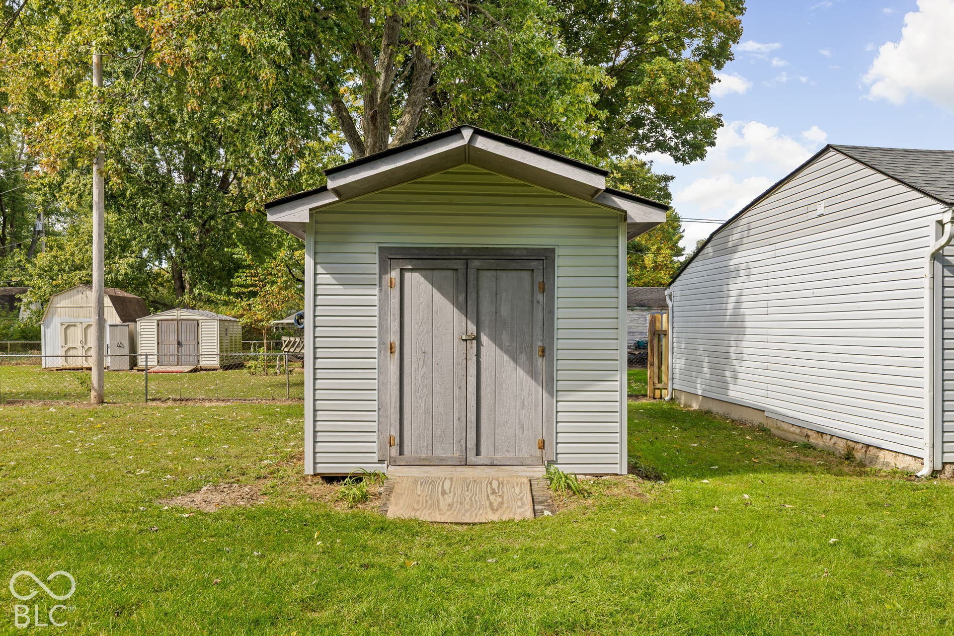 Storage building featuring light-colored horizontal siding, a gabled roof, and double entry doors