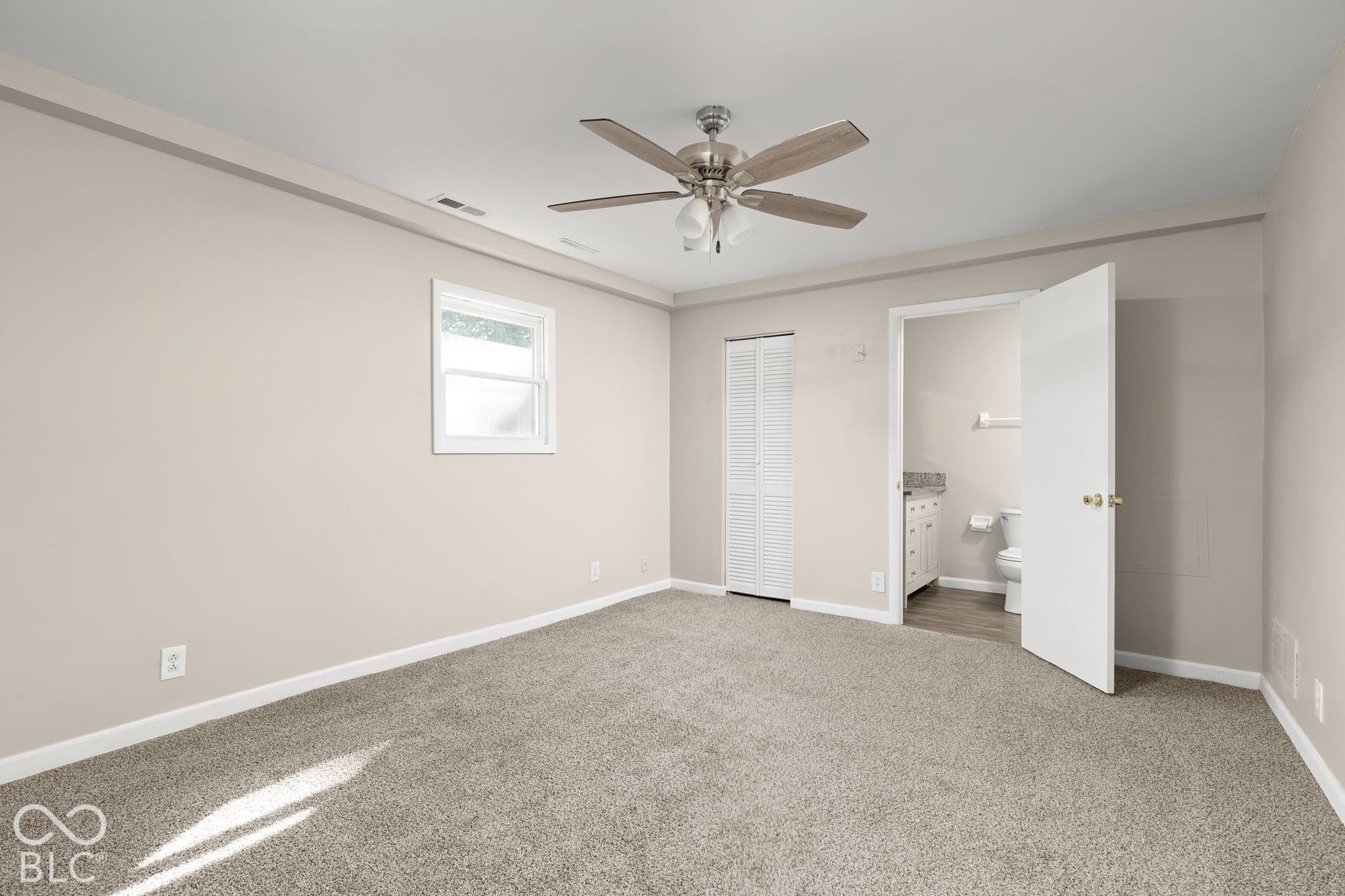 Interior space featuring neutral-toned carpeting, a ceiling fan with multi-blade light fixture, a single-window wall, and a bifold closet door