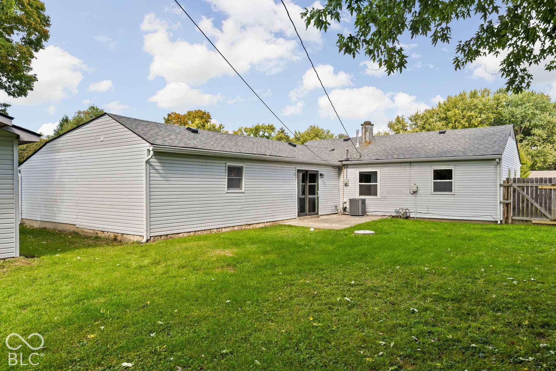 Exterior view featuring horizontal siding, asphalt shingle roofing, a concrete patio, and a fenced-in lawn