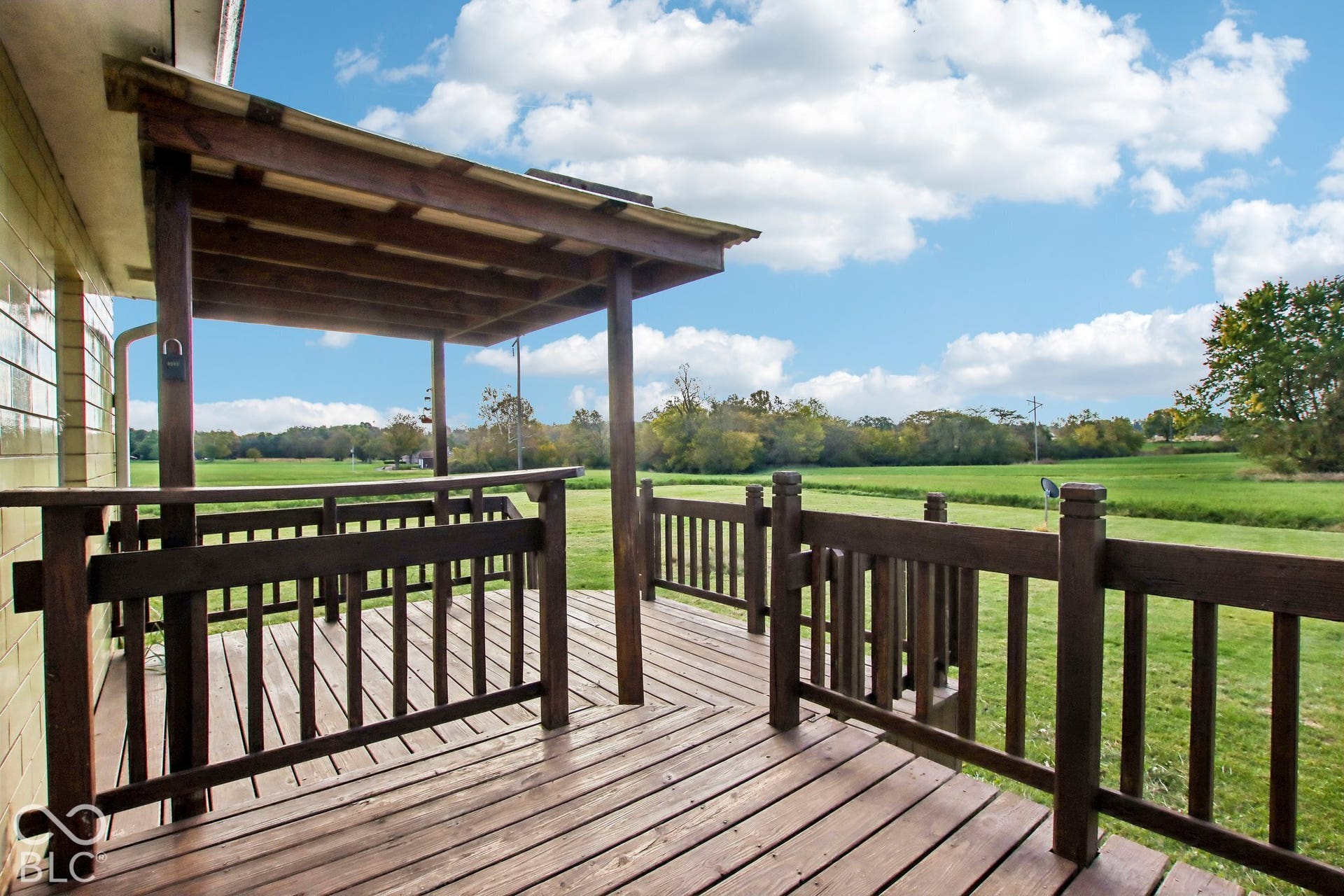 4469 E 400 S, Franklin, IN 46131 Raised wooden deck featuring a covered area with a built-in railing, overlooking expansive open acreage