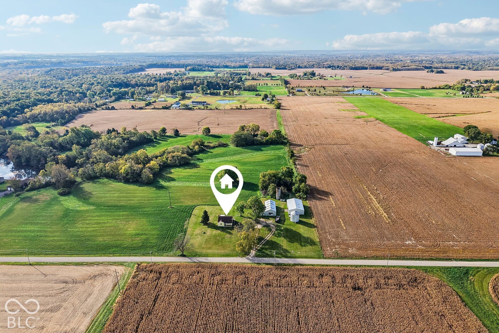 4469 E 400 S, Franklin, IN 46131 Aerial perspective of a rural property featuring expansive acreage, multiple outbuildings, a grain silo, and mature perimeter trees