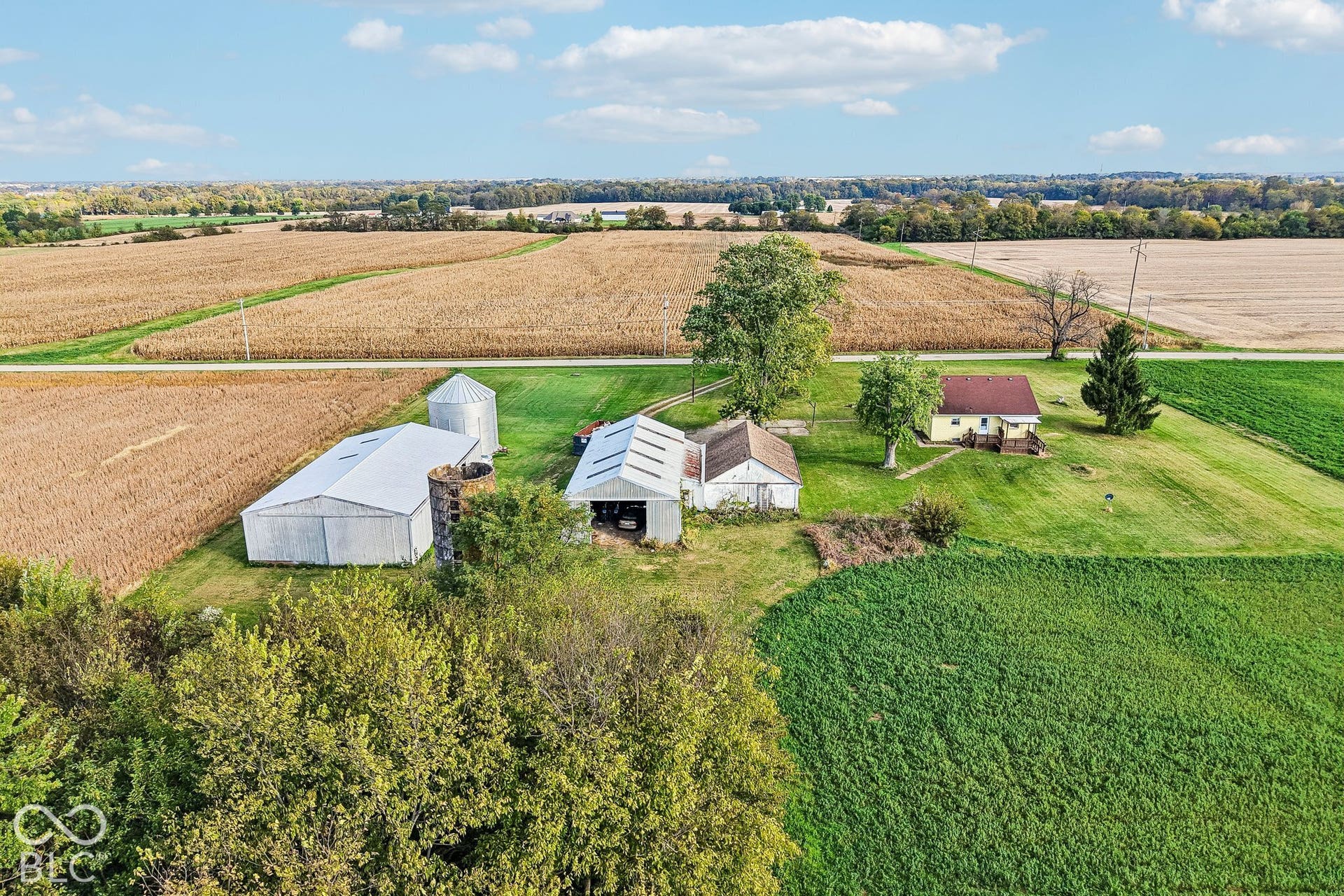 4469 E 400 S, Franklin, IN 46131 Aerial perspective of rural acreage featuring multiple outbuildings, metal-roofed structures, a grain silo, and expansive open fields