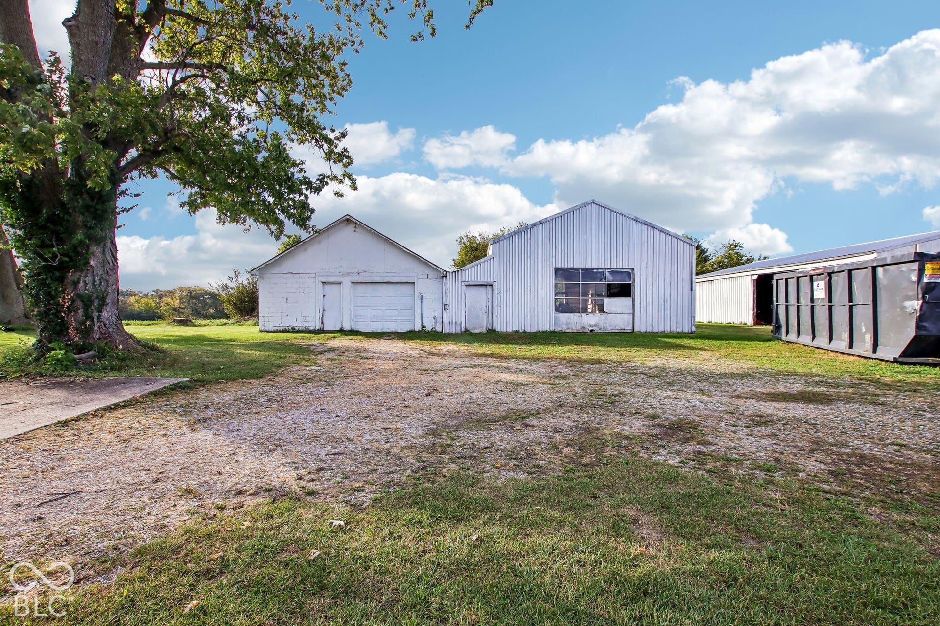 4469 E 400 S, Franklin, IN 46131 Detached metal-sided outbuildings featuring a gravel-surfaced drive, exterior man-doors, and mature trees on expansive grounds