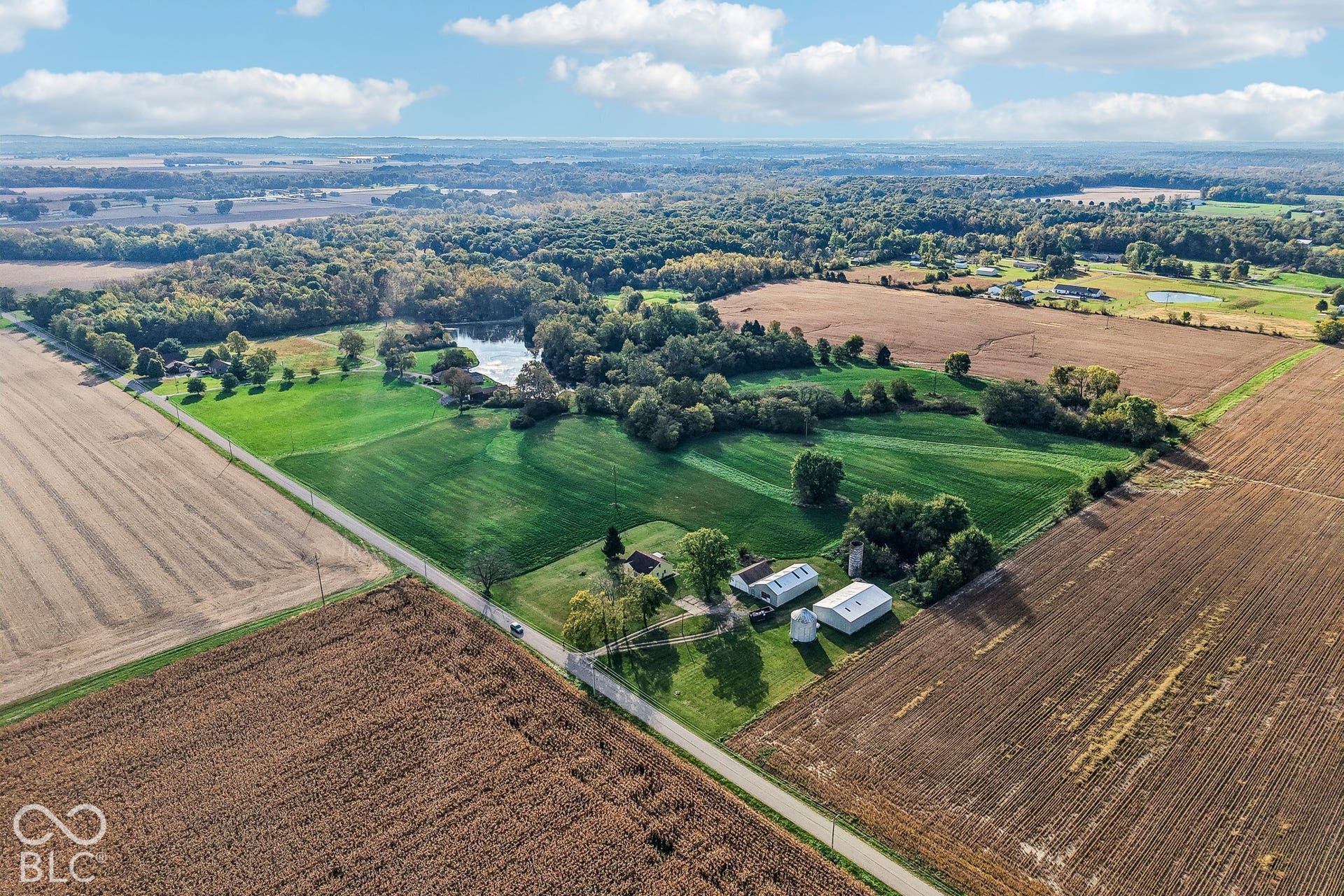 4469 E 400 S, Franklin, IN 46131 Aerial view of expansive acreage featuring cultivated fields, mature tree lines, a private pond, and multiple outbuildings
