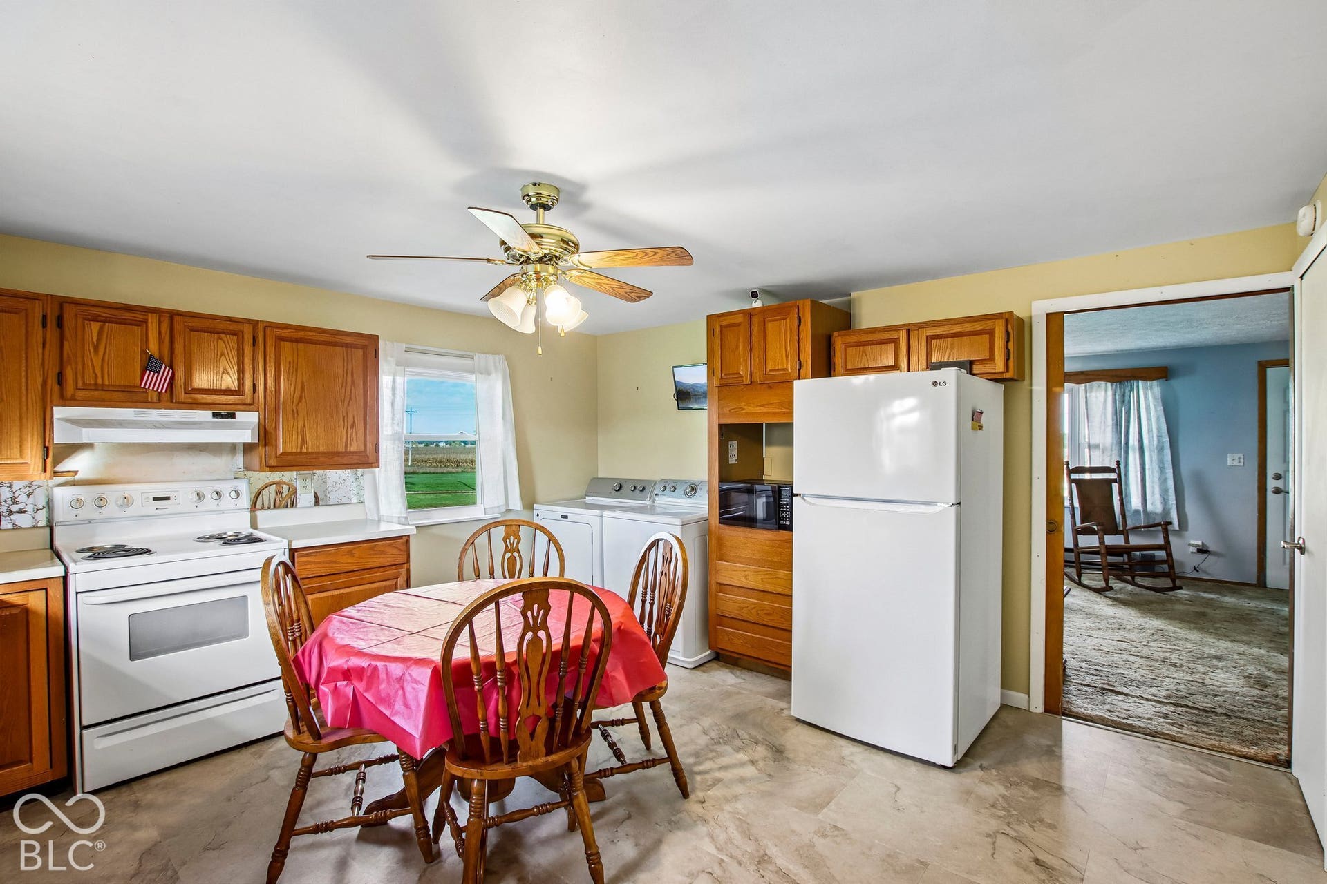 4469 E 400 S, Franklin, IN 46131 Kitchen featuring oak-finish cabinetry, white appliances, integrated laundry area, and ceiling fan with lighting fixture