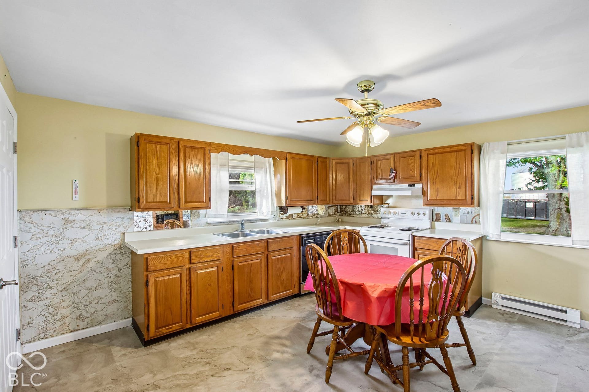 4469 E 400 S, Franklin, IN 46131 Kitchen featuring medium-tone wood cabinetry, solid-surface countertops, a dual-basin stainless steel sink, and a ceiling-mounted light fixture with integrated fan