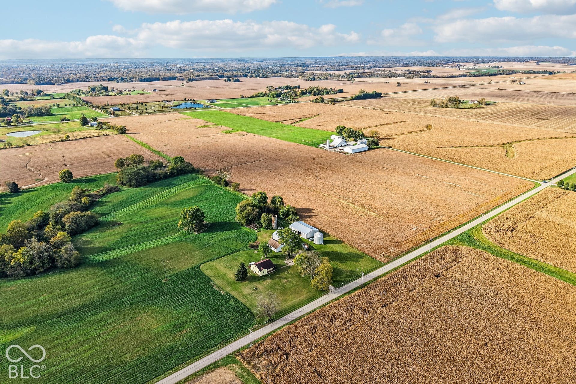 4469 E 400 S, Franklin, IN 46131 Aerial view of expansive acreage featuring cultivated crop fields, mature trees, a multi-structure farmstead, and direct road frontage