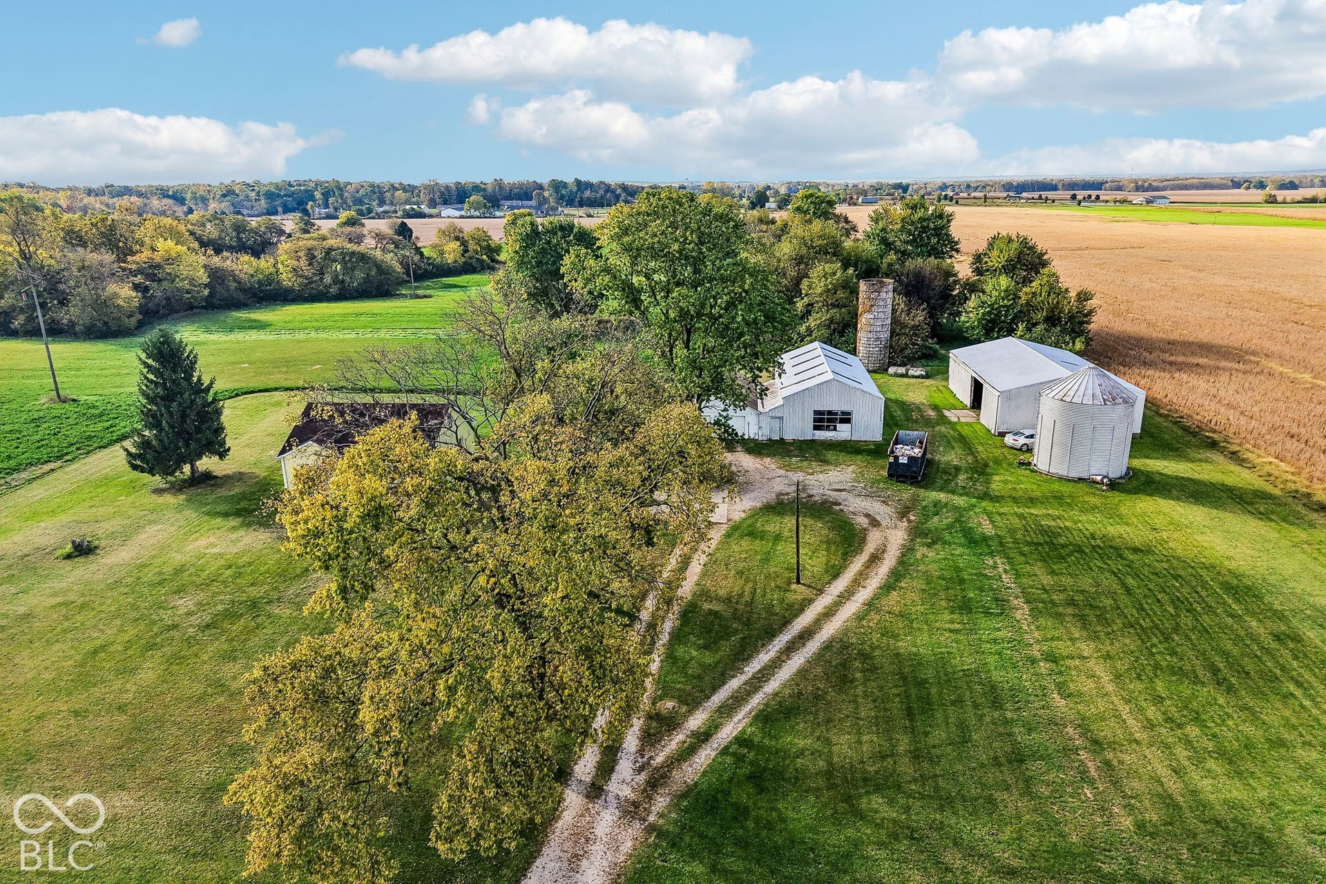 4469 E 400 S, Franklin, IN 46131 Aerial perspective of expansive acreage featuring multiple outbuildings, metal-sided structures, a grain silo, and mature trees