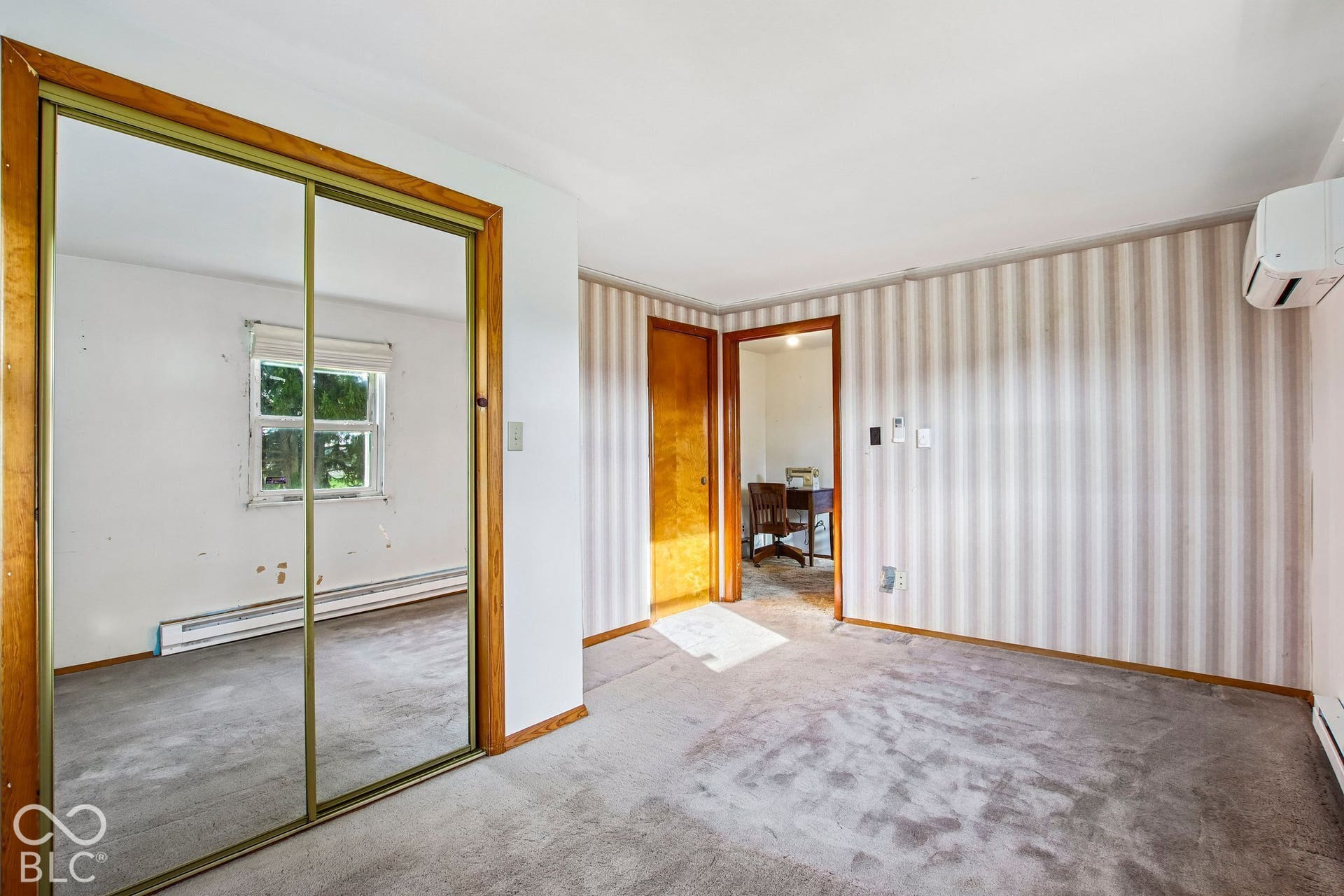 4469 E 400 S, Franklin, IN 46131 Wall-mounted climate control unit, floor-to-ceiling mirrored sliding closet doors, wood-frame door, and striped wallpaper
