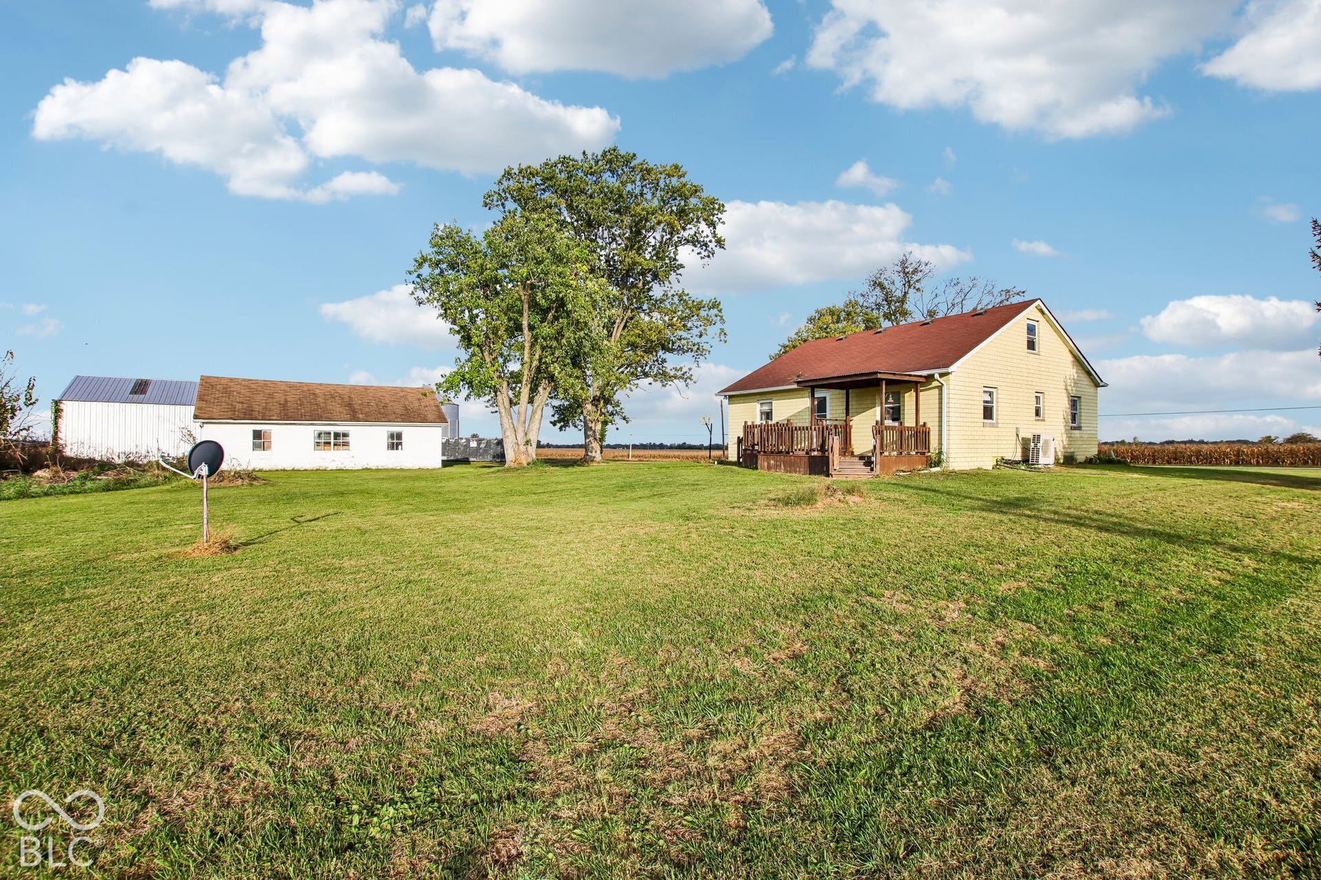 4469 E 400 S, Franklin, IN 46131 Expansive lot featuring mature trees, a detached outbuilding with a metal roof, and a residence with an attached wooden deck