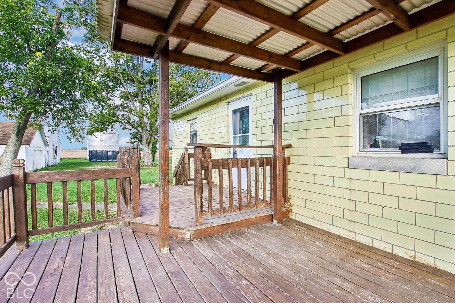 4469 E 400 S, Franklin, IN 46131 Exterior wood deck featuring a covered porch area with a timber support post, wood railing, and light-colored masonry siding