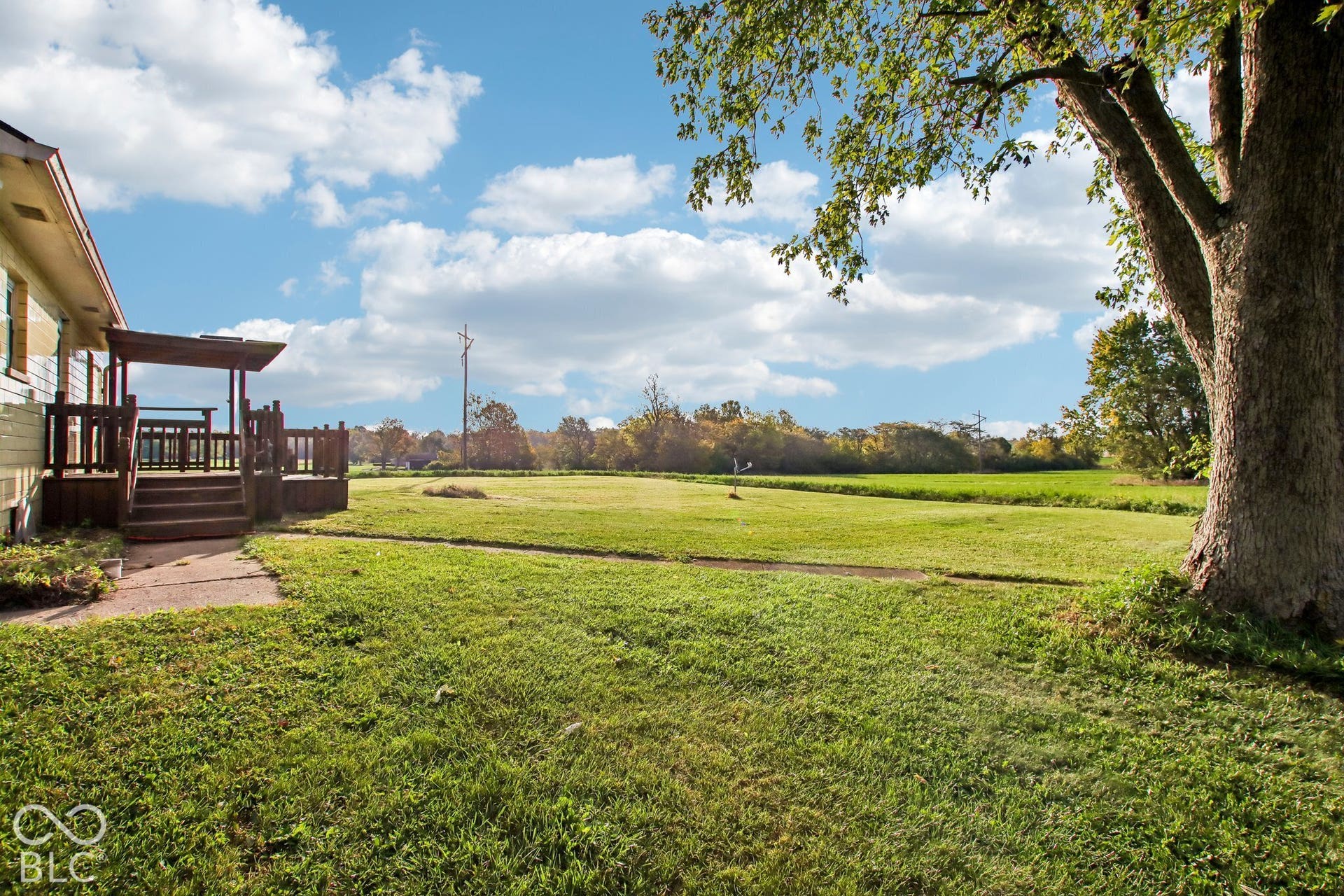 4469 E 400 S, Franklin, IN 46131 Expansive backyard featuring a large open lawn, mature trees, and a wooden deck with a built-in pergola