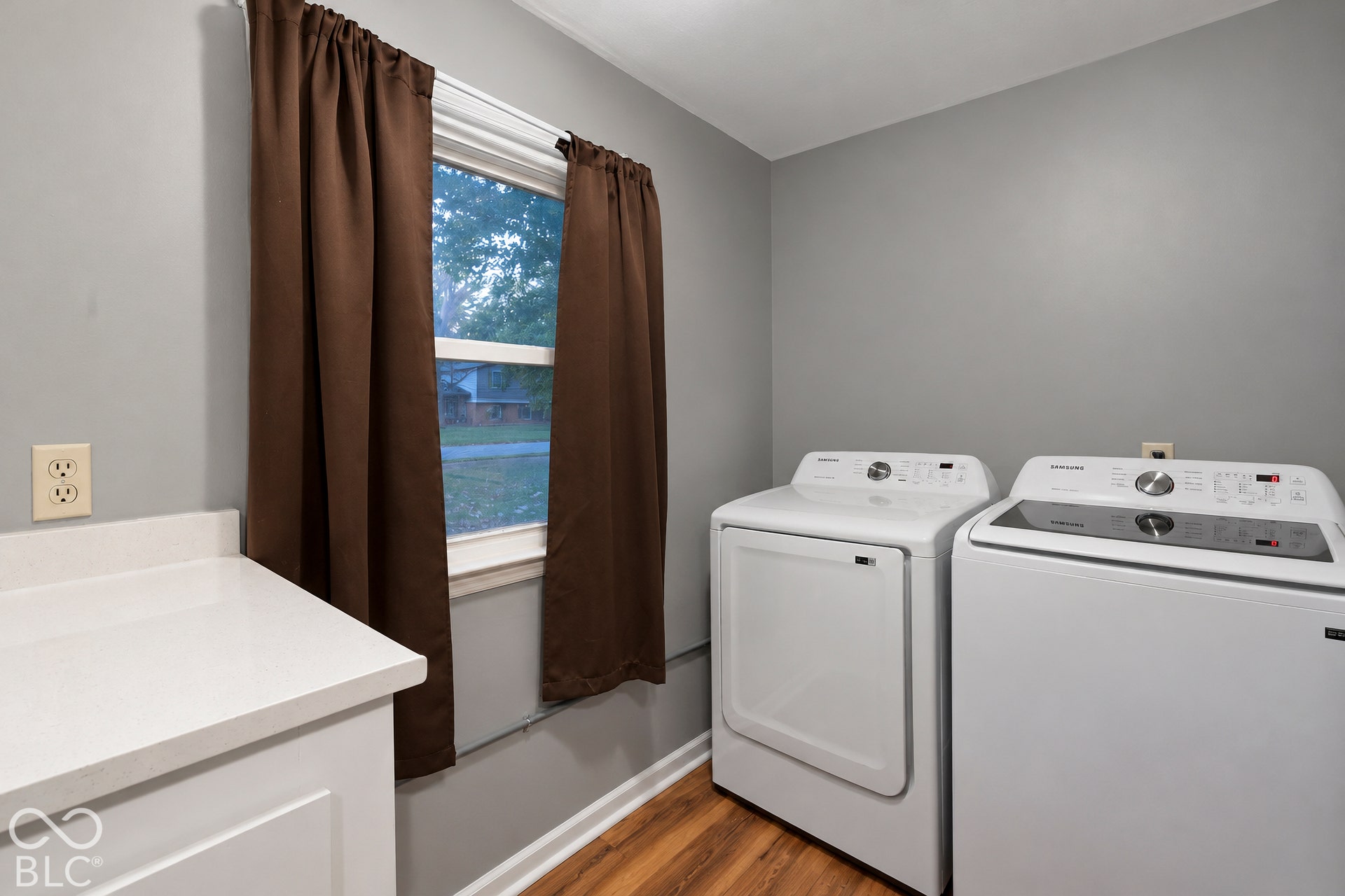 Laundry room featuring wood-finish flooring, white built-in cabinetry, and a countertop surface