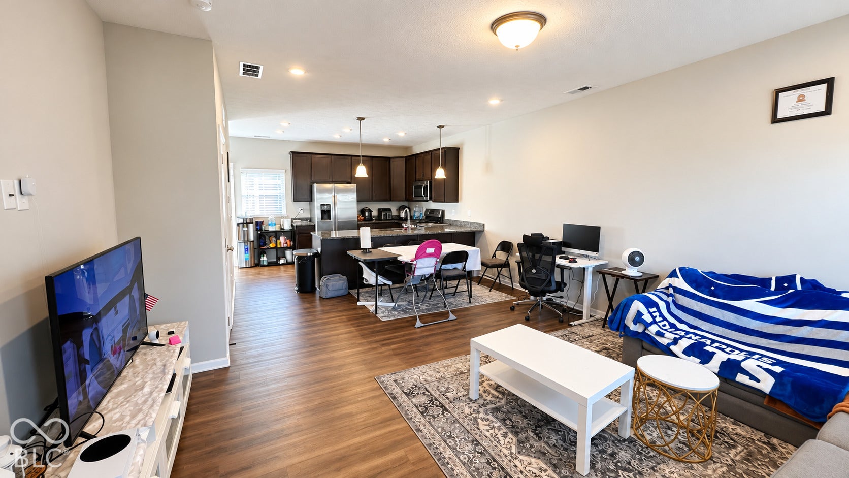 Open-concept space featuring wood-finish flooring, recessed lighting, and kitchen cabinetry with a central island