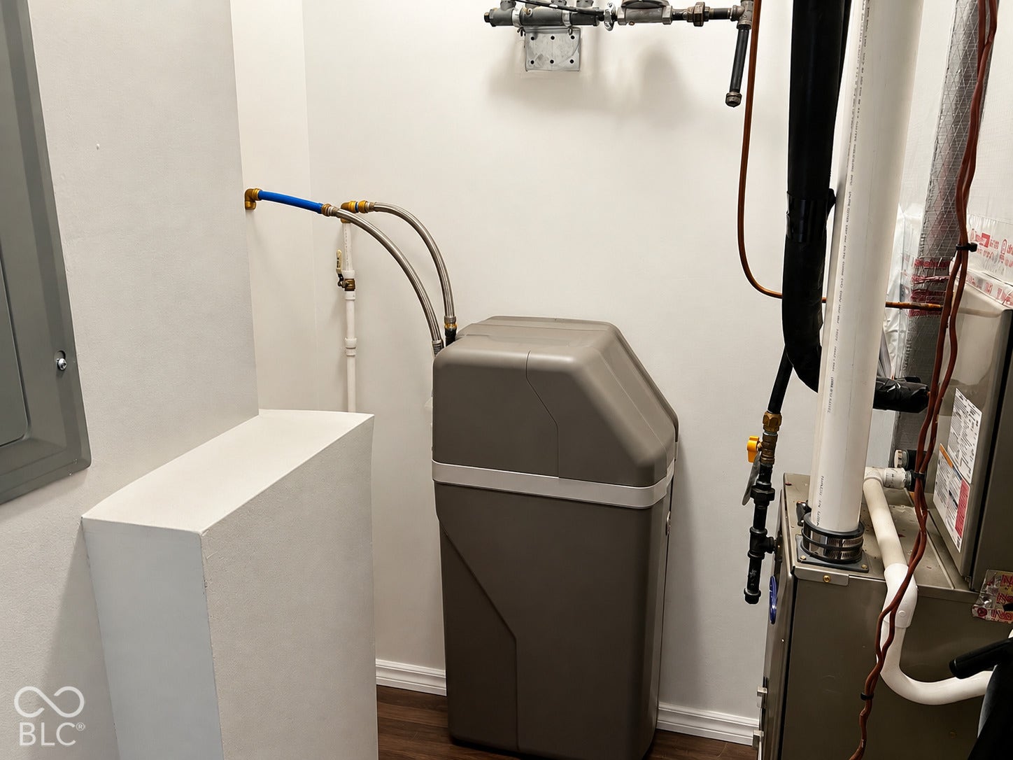 Water treatment system with metallic braided supply lines, PVC piping, and wood-finish flooring