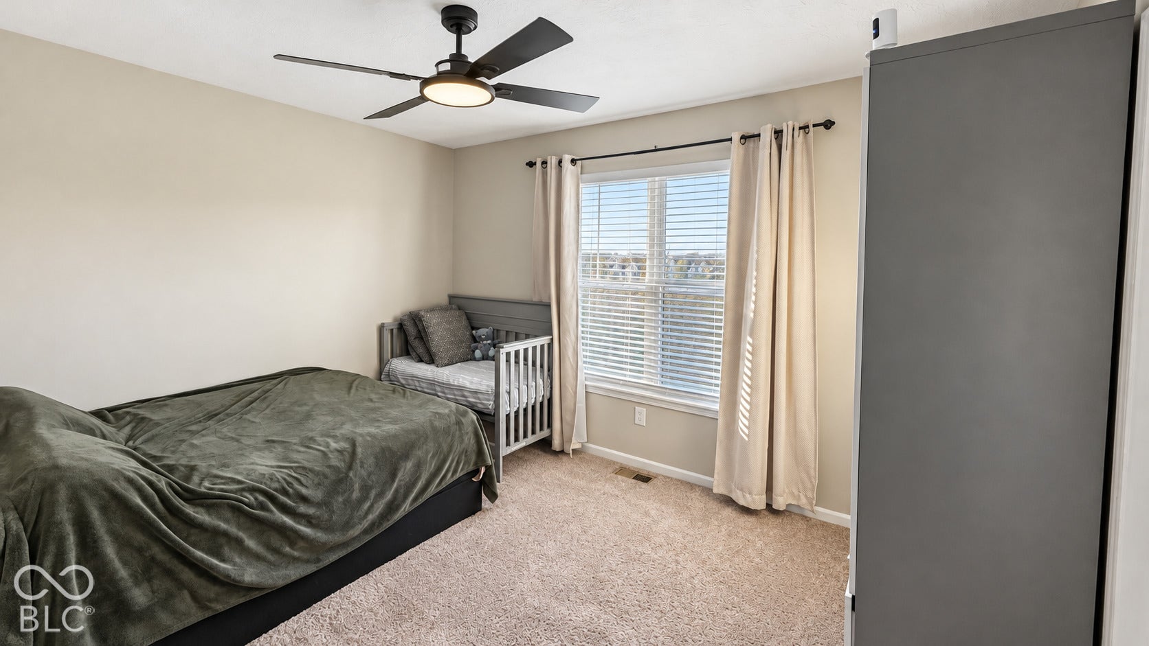 Neutral-toned room featuring wall-to-wall carpeting, a large window with horizontal blinds, and an integrated ceiling fan with light fixture