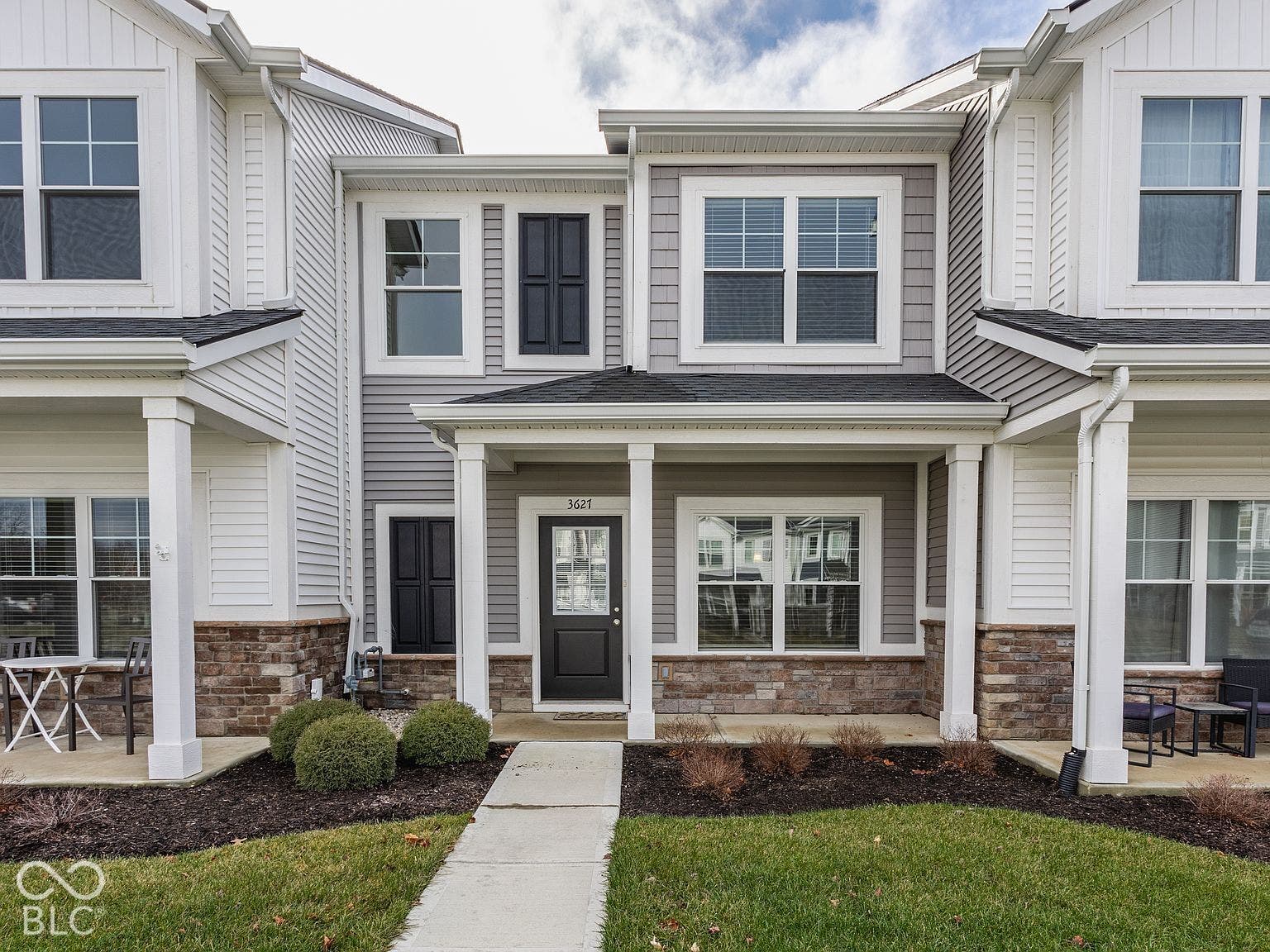 Exterior facade featuring a combination of horizontal lap siding, vertical shake siding, and stone veneer, complemented by a covered front porch with square columns
