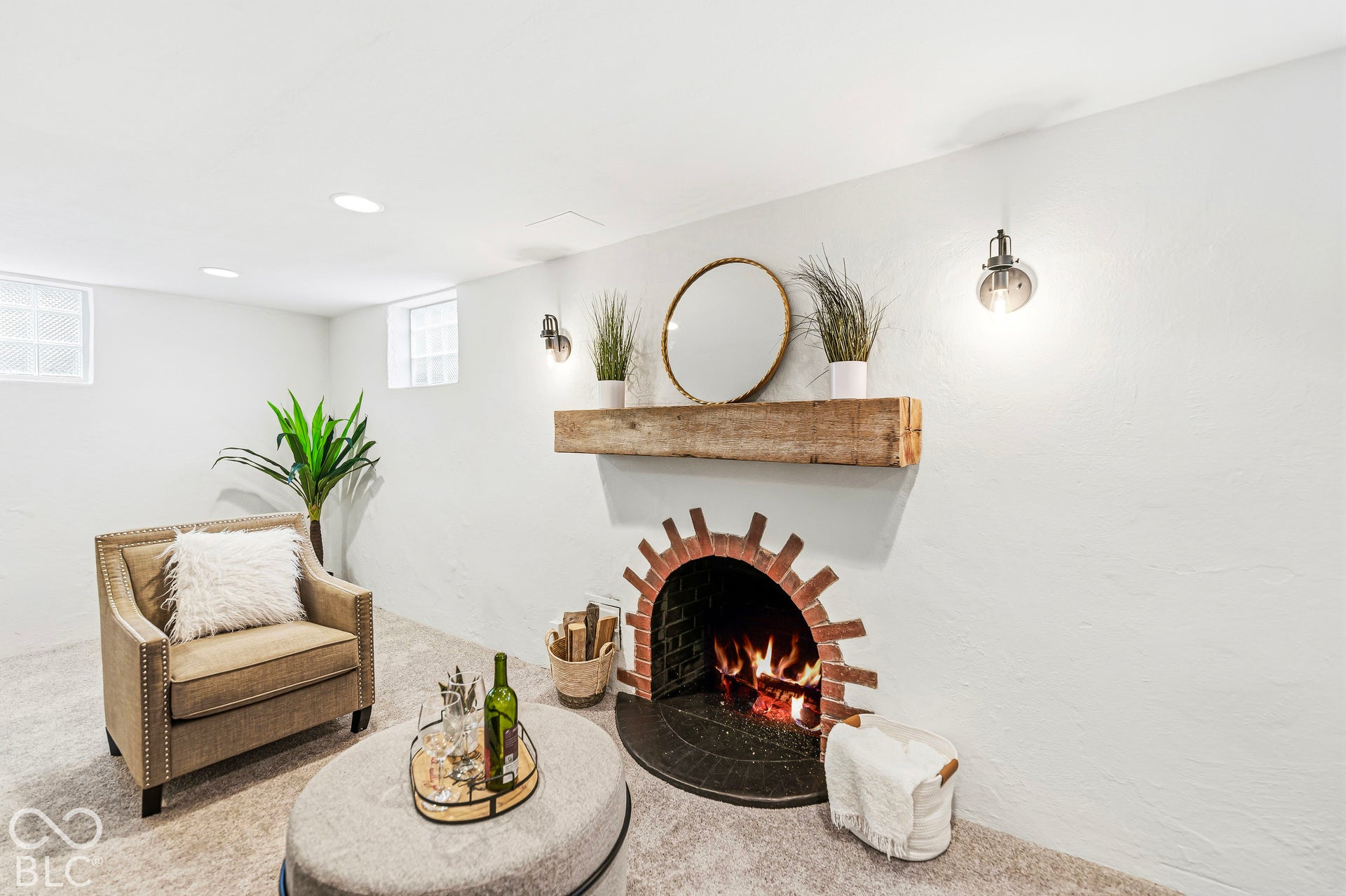 Fireplace with a decorative red brick arched surround, natural stone hearth, and a reclaimed wood mantel, complemented by recessed ceiling lighting and wall-mounted metal sconces