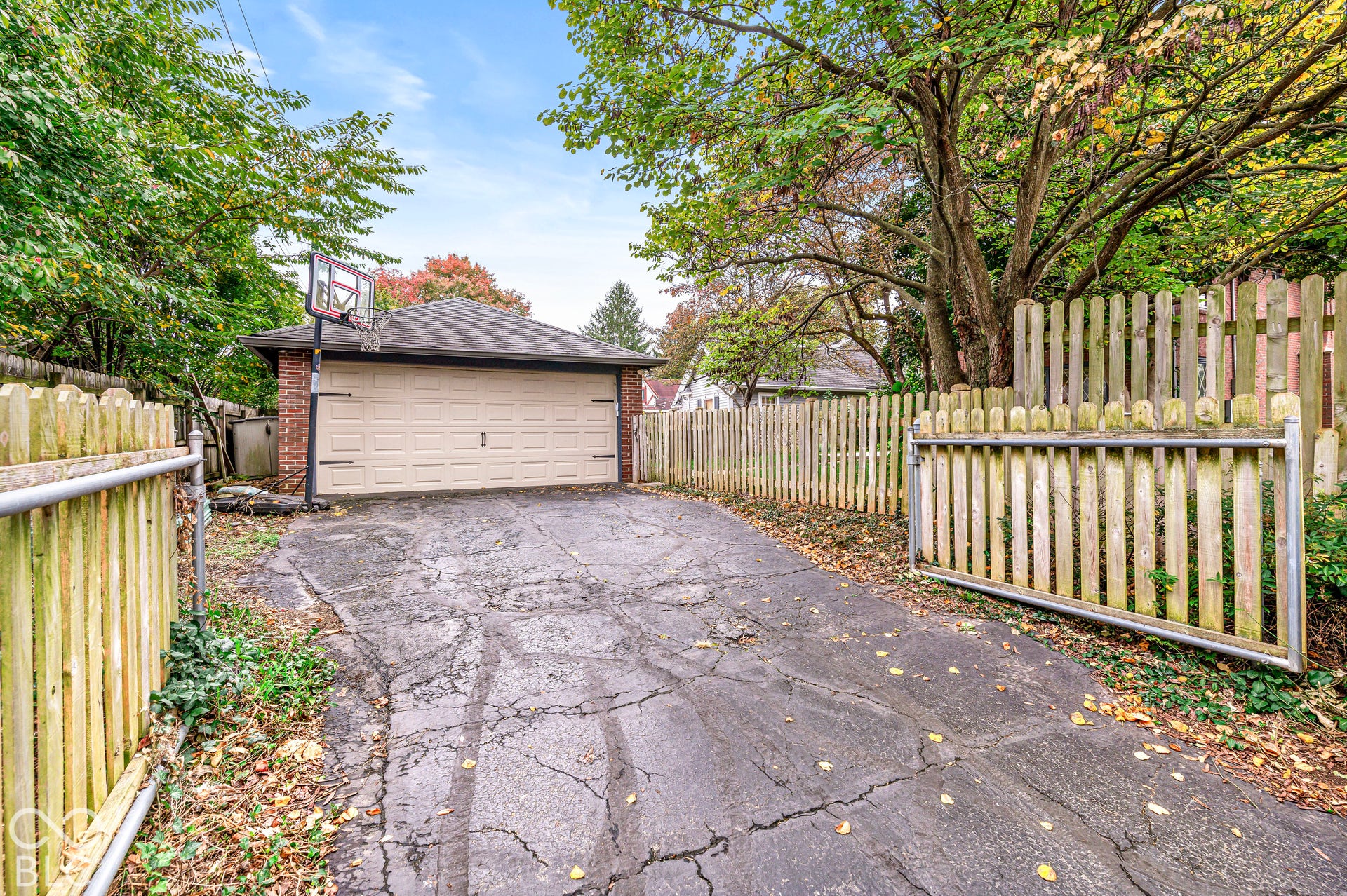 Detached brick garage featuring a multi-panel overhead door, asphalt driveway, and surrounding wood privacy fencing